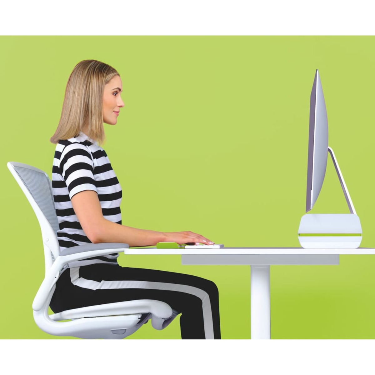 Kobieta siedzi przy biurku z komputerem, pisząc na klawiaturze. Zielone tło.