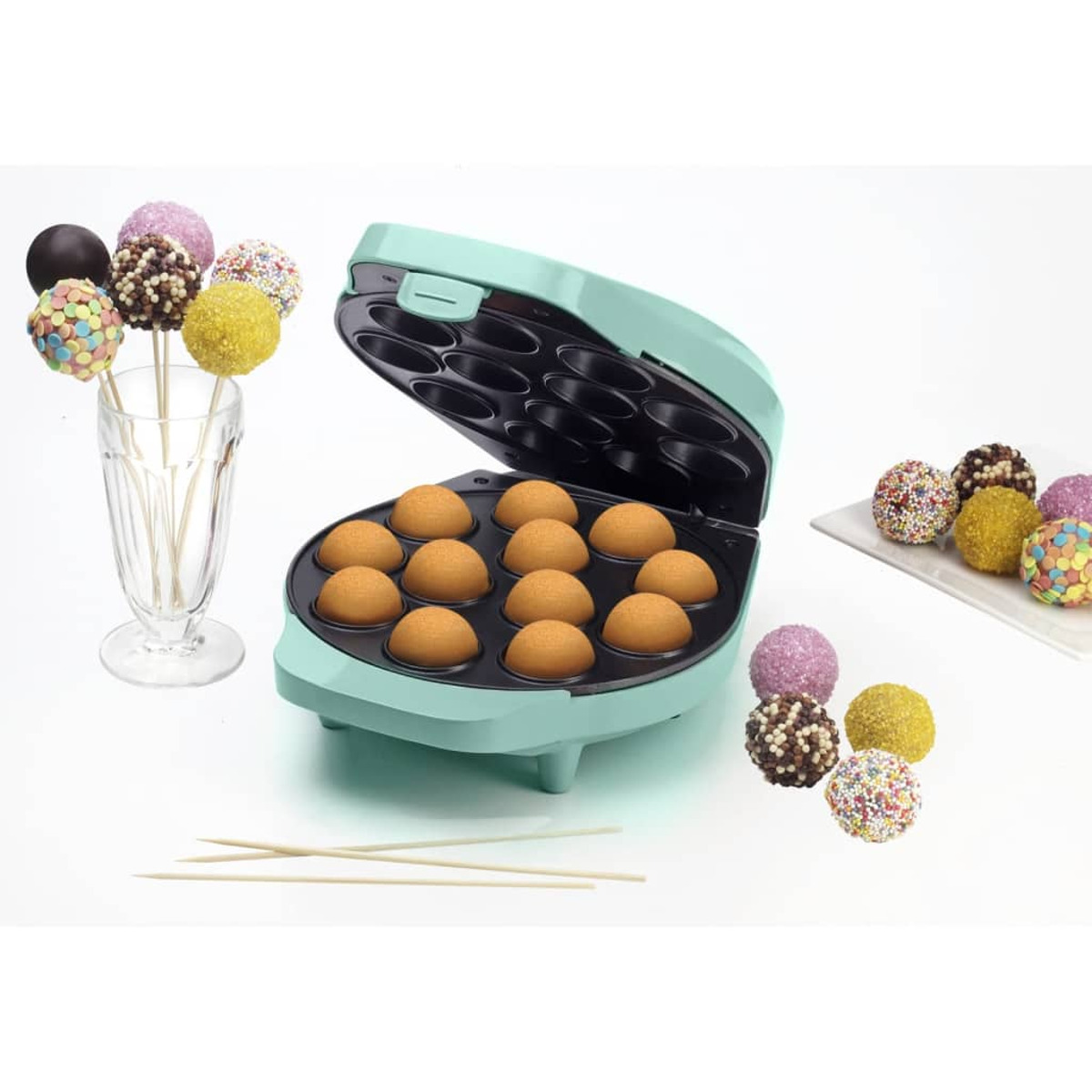 Una máquina para hacer cake pops turquesa con cake pops horneados dentro y decorados en palitos.