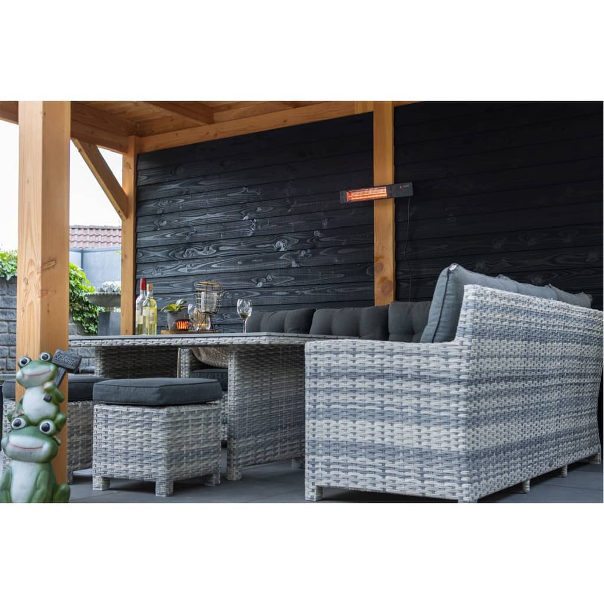 Terrasse mit Tisch, Stühlen, Kissen und Infrarotheizung an einer schwarzen Wand.