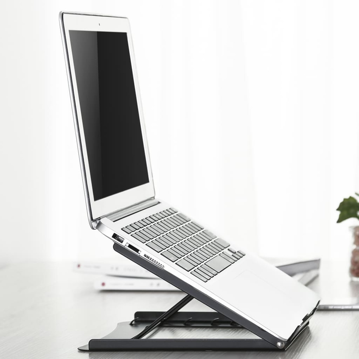 Ein Laptop auf einem schwarzen Ständer, offen, zum Betrachter geneigt.