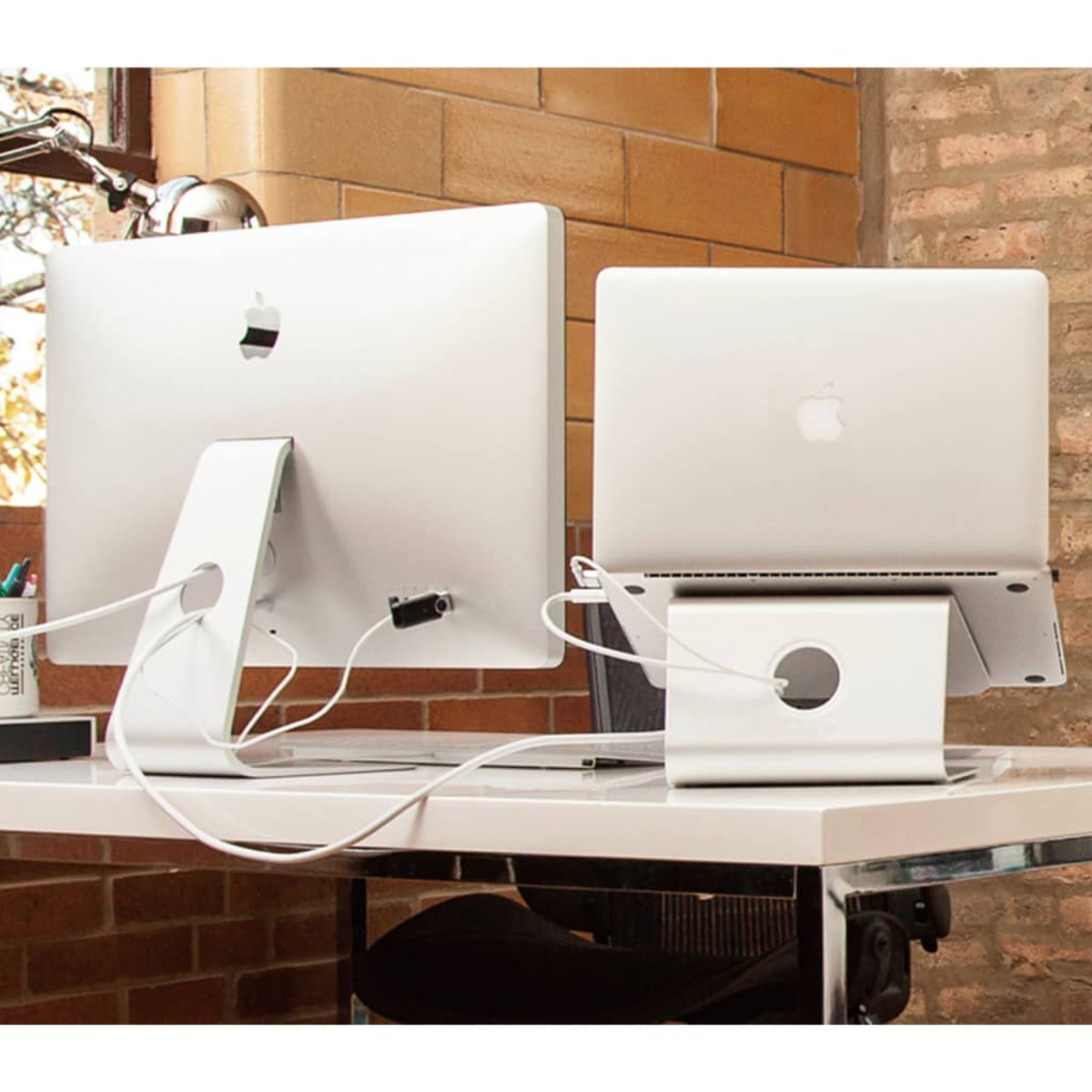 Un iMac e un MacBook sono su una scrivania. Si vedono cavi.
