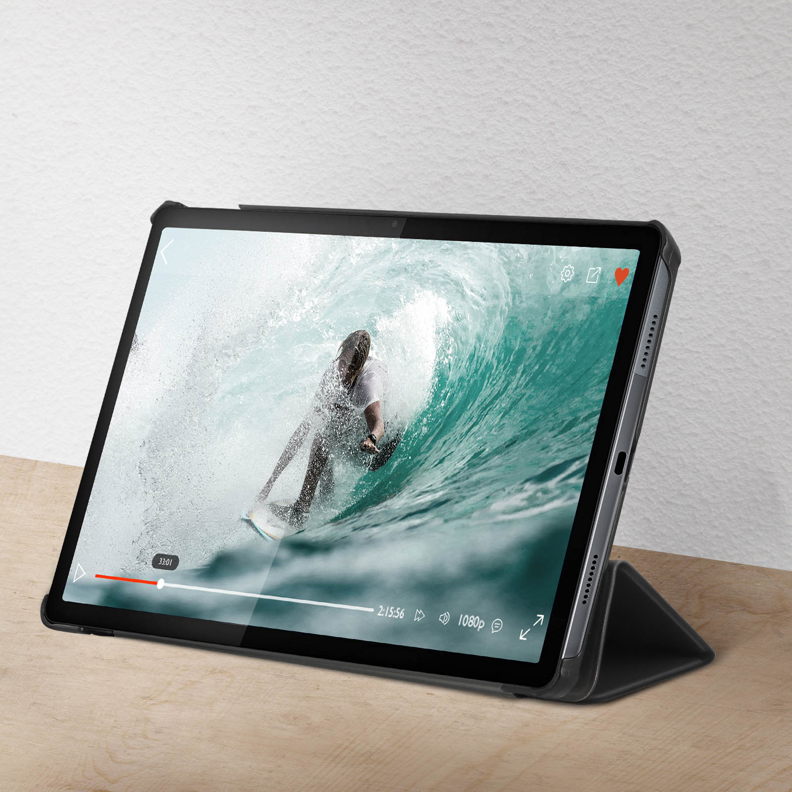 Tablet che riproduce un video di una persona che fa surf su un'onda. Una superficie in legno di colore chiaro.