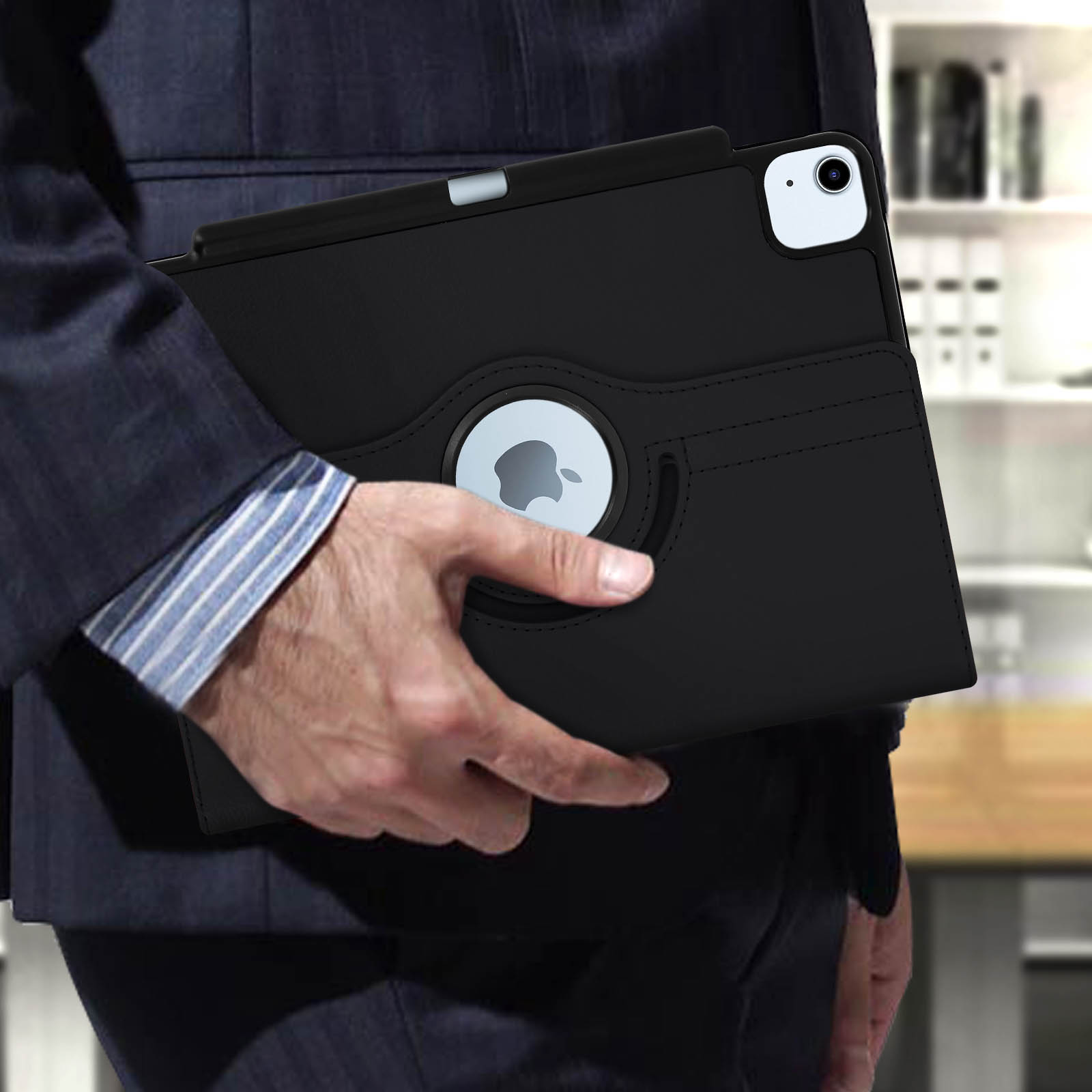 Una persona tiene in mano un iPad nero in una custodia protettiva. Logo Apple visibile.