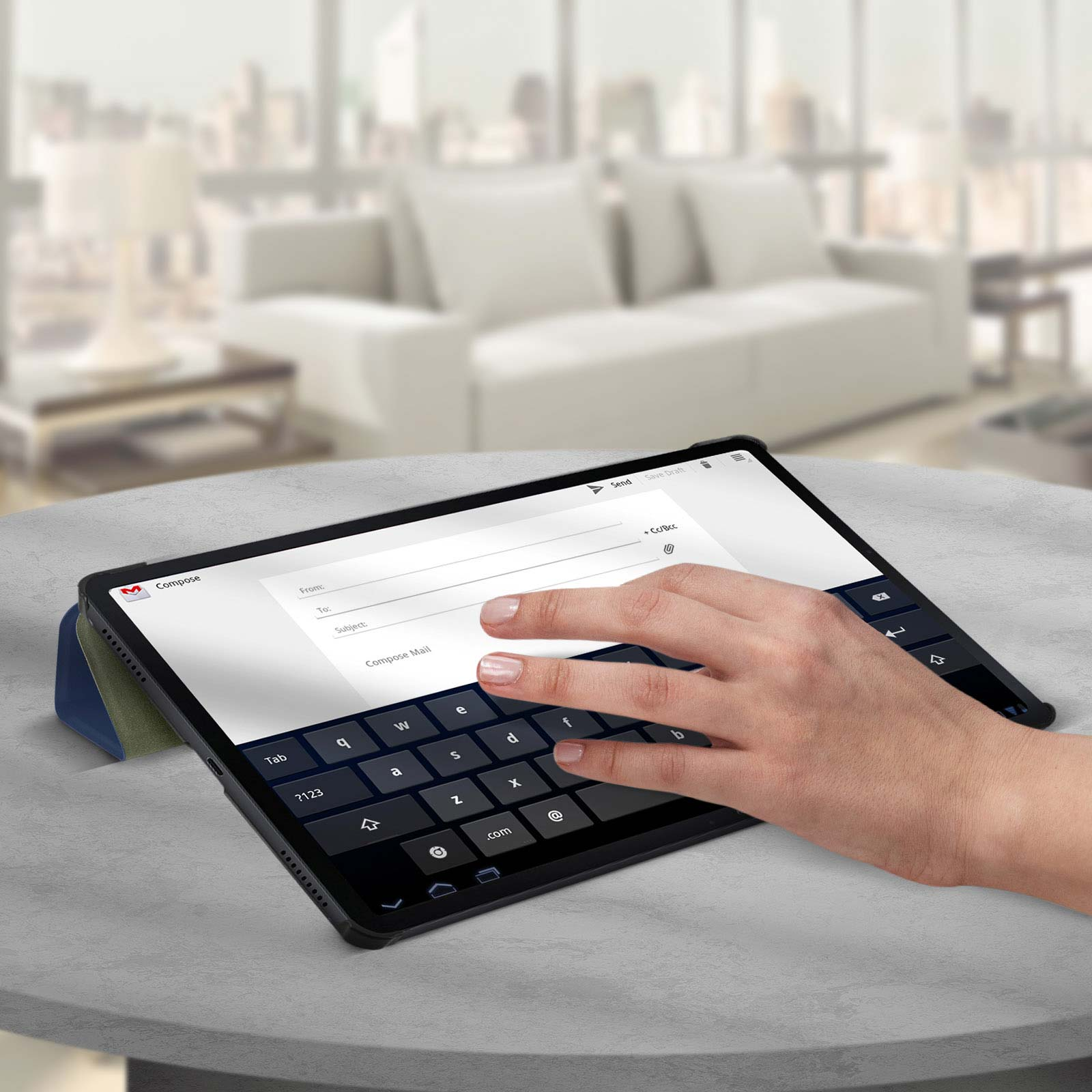 Tablet su un tavolo con una mano che tocca lo schermo. Schermo di composizione email.