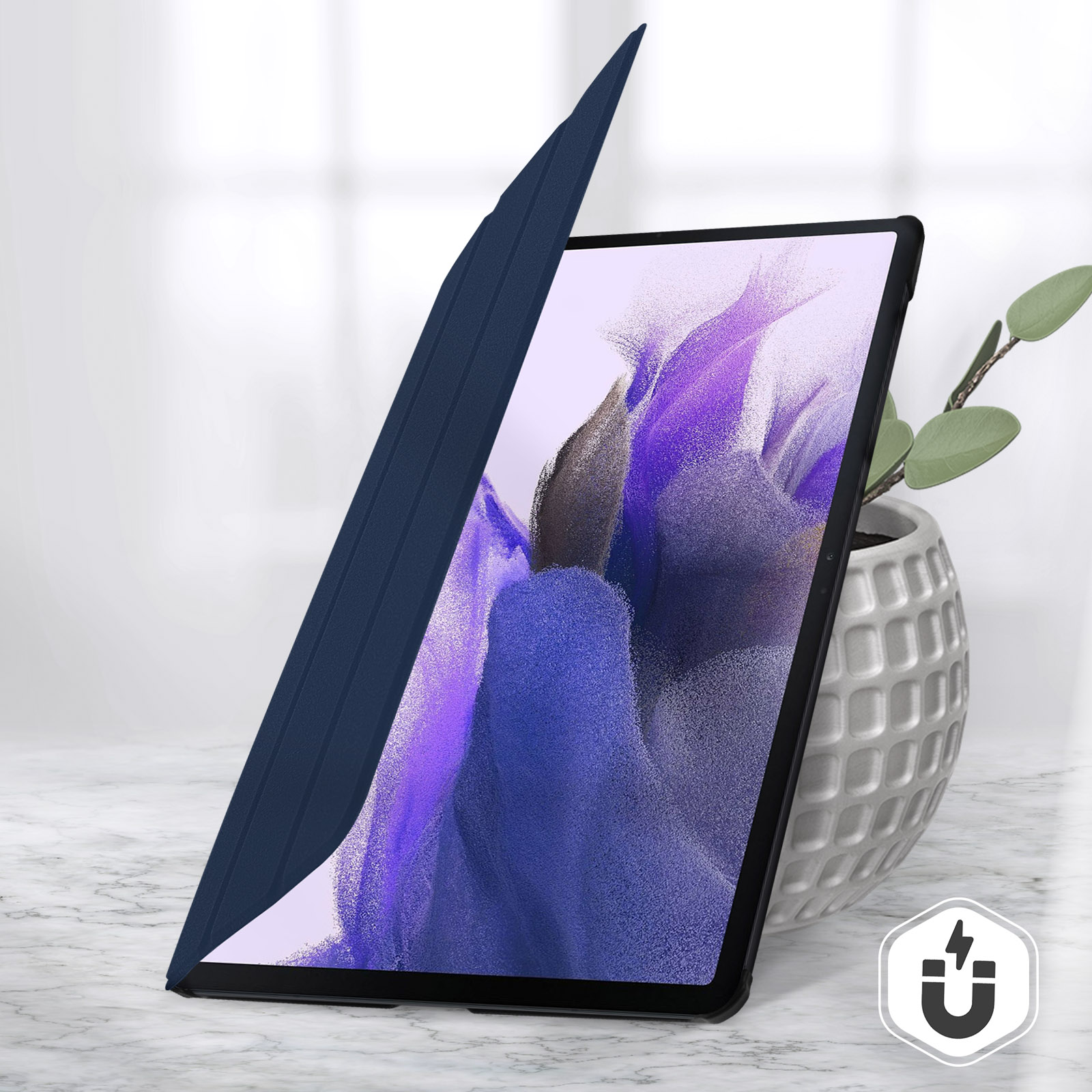 Tablet con cover blu, parzialmente aperto, su tavolo marmo. Pianta in vaso.