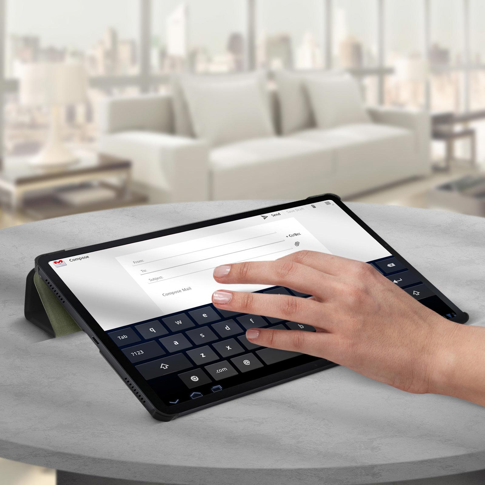 La mano di una persona interagisce con un tablet, componendo un'e-mail con una tastiera visualizzata.