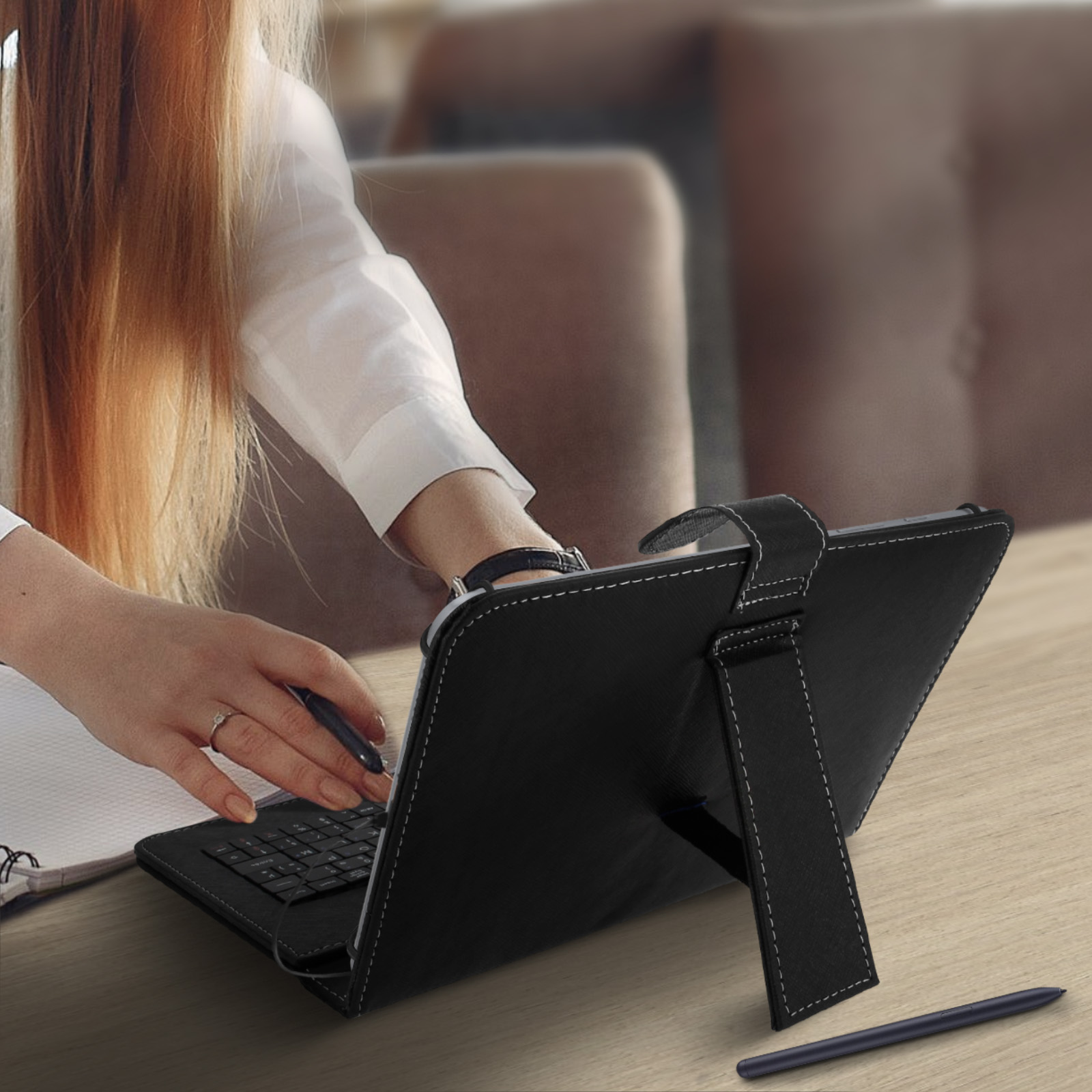 Mujer usando una tableta con teclado, con un lápiz óptico sobre una mesa de madera.