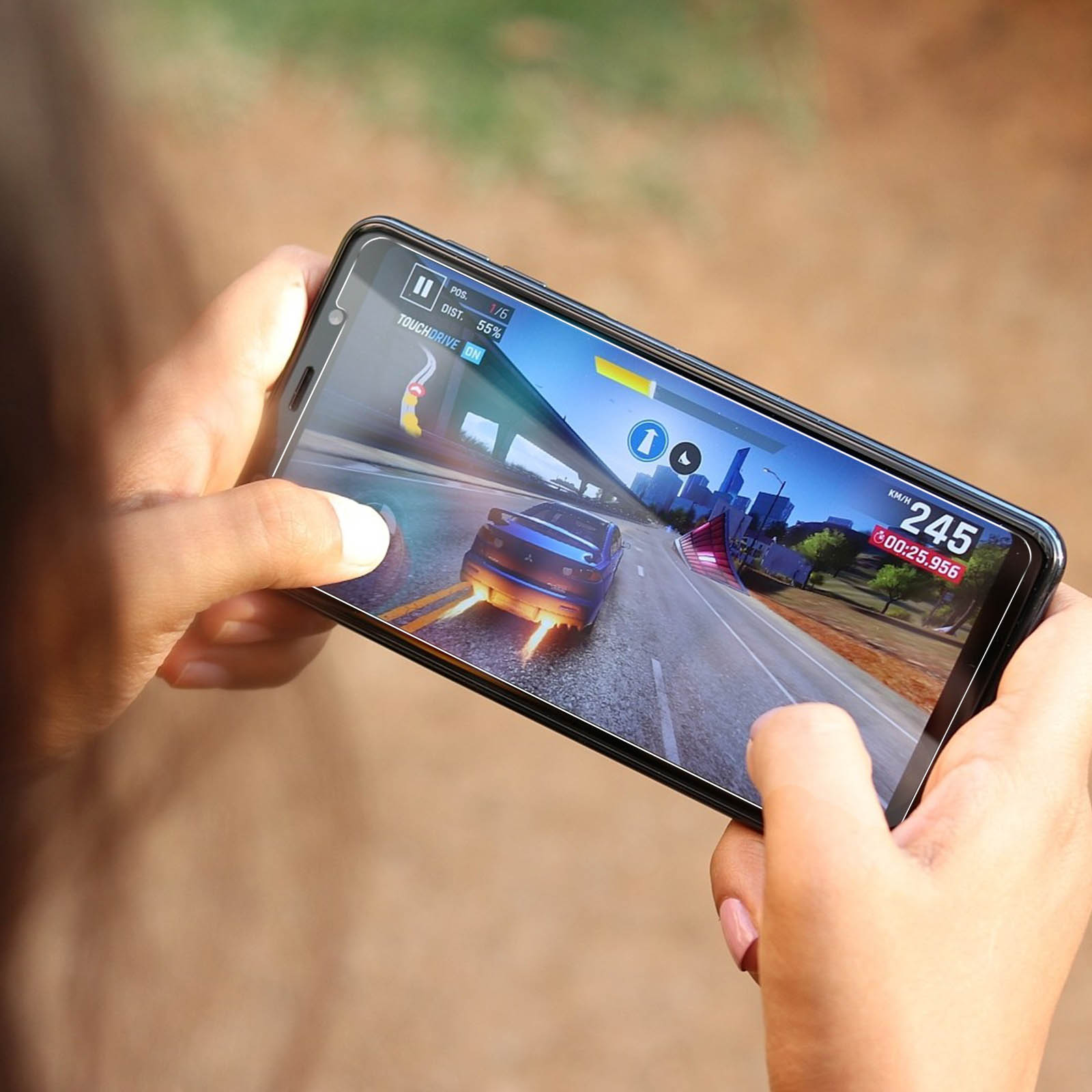 Mani che tengono un telefono che mostra un gioco di corse. Un'auto blu corre su una pista.