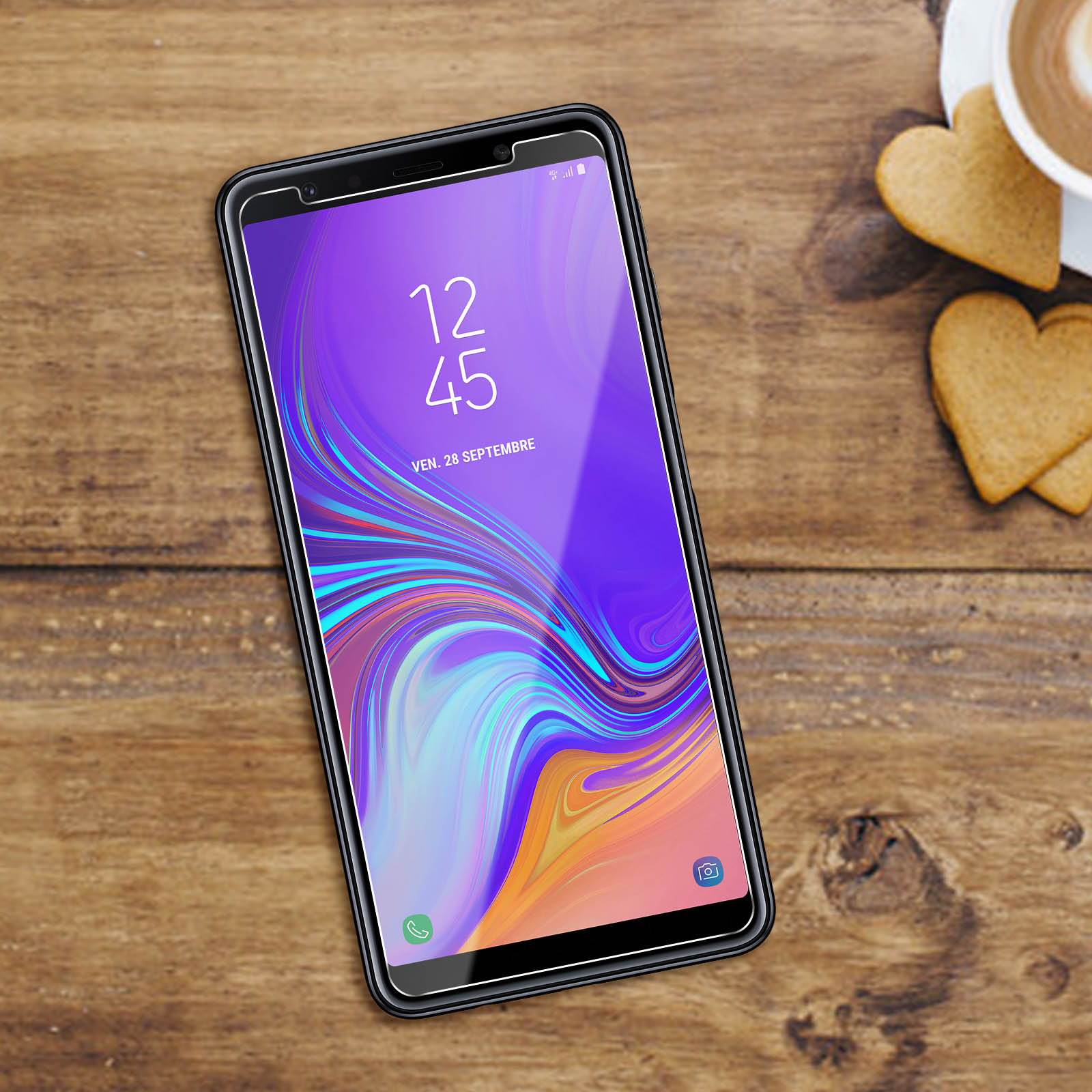 Smartphone su un tavolo di legno, mostra l'ora e la data. Accanto al telefono, due biscotti.