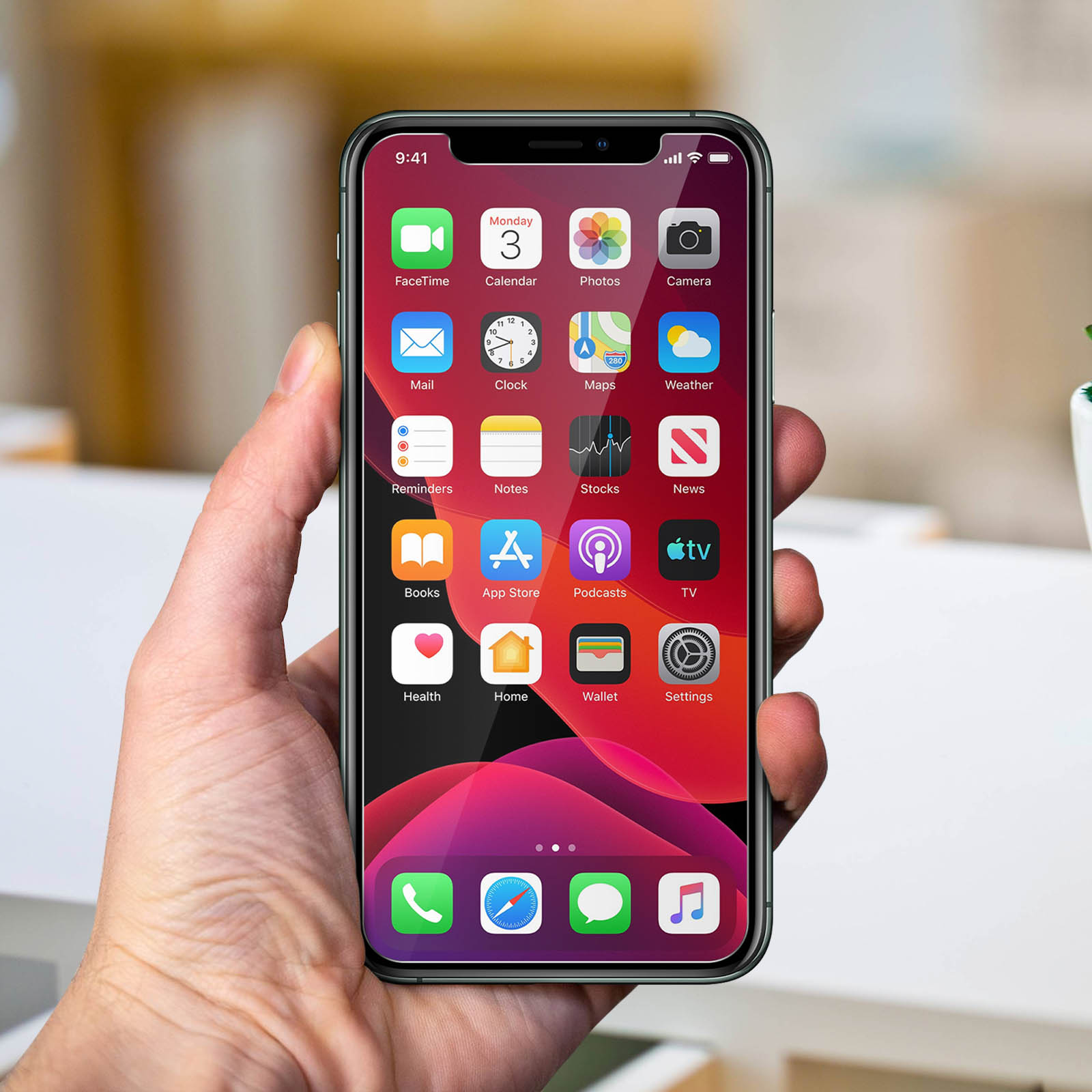 Hand holding a phone displaying app icons. The phone has a red background.