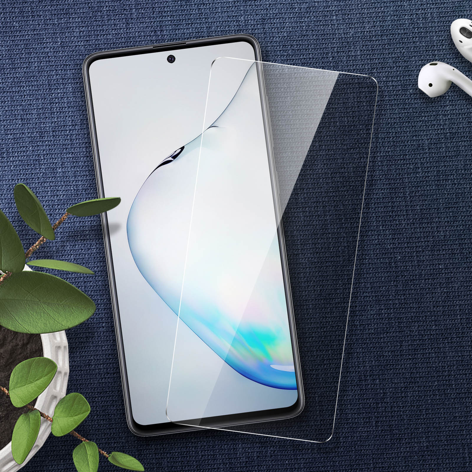 Smartphone avec protecteur d'écran et écouteurs sur surface bleue avec plante.