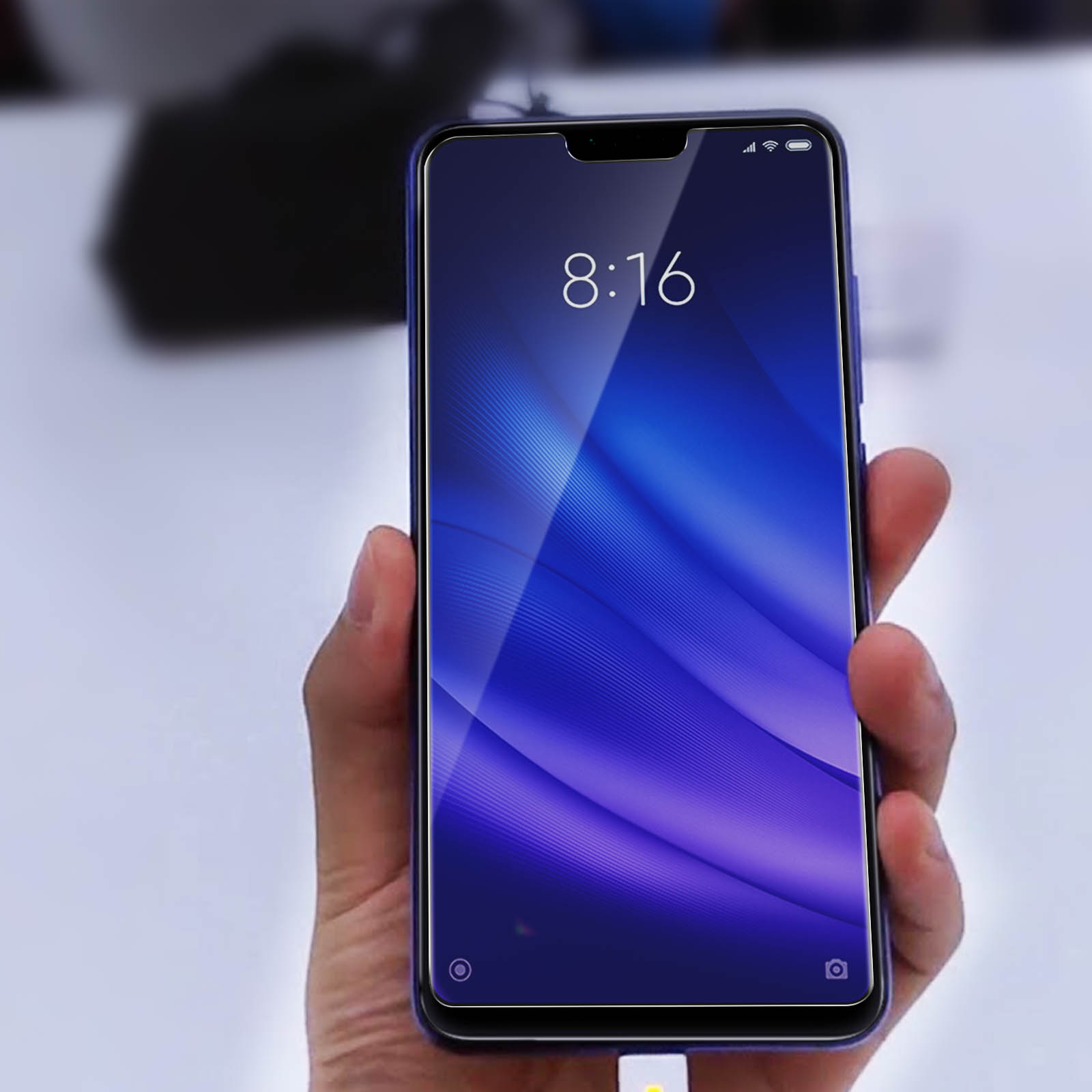 Mano che tiene uno smartphone con schermo blu che mostra ora e barre del segnale.