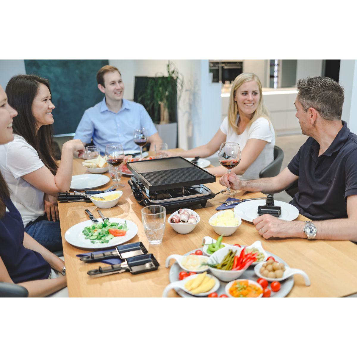 Sechs Personen an einem Tisch, die eine Mahlzeit genießen, mit Essen und Wein.