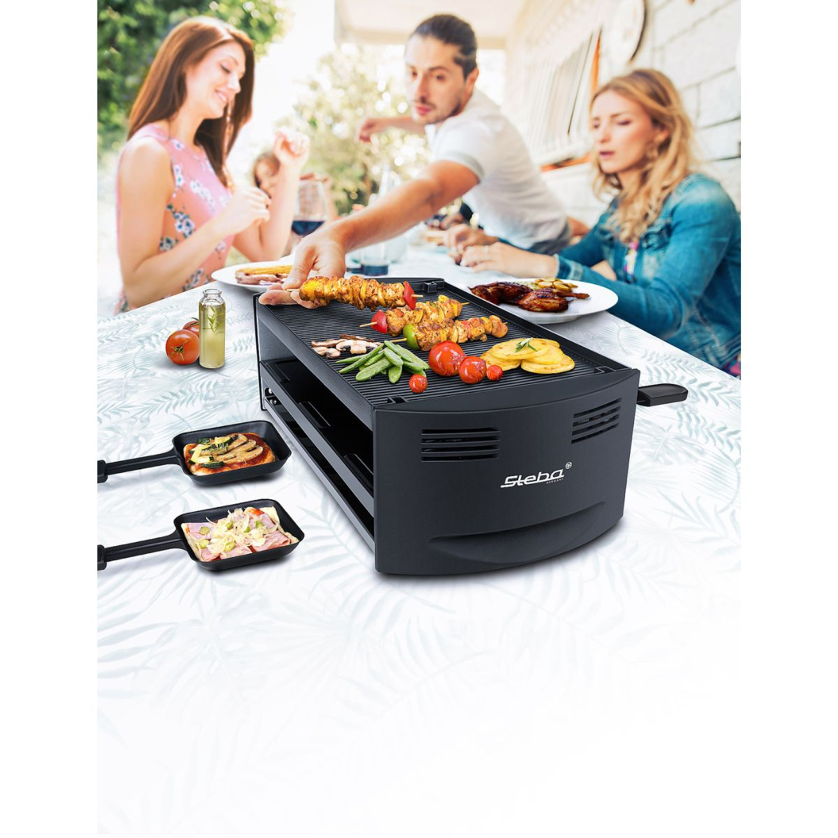 Leute grillen draußen Essen auf einem schwarzen Grill. Am Tisch sitzen Leute.