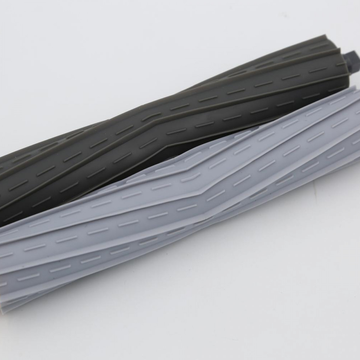 Dwie ciemnoszare i jasnoszare szczotki rolkowe do odkurzacza leżą obok siebie.