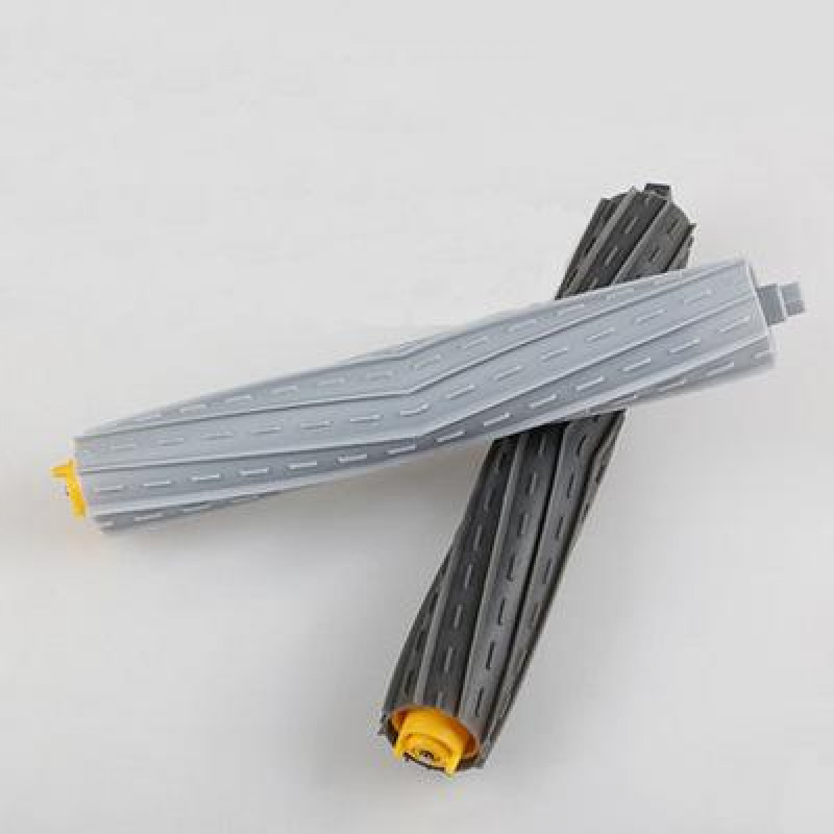 Dwie szare i czarne szczotki rolkowe do odkurzacza leżą na białej powierzchni.