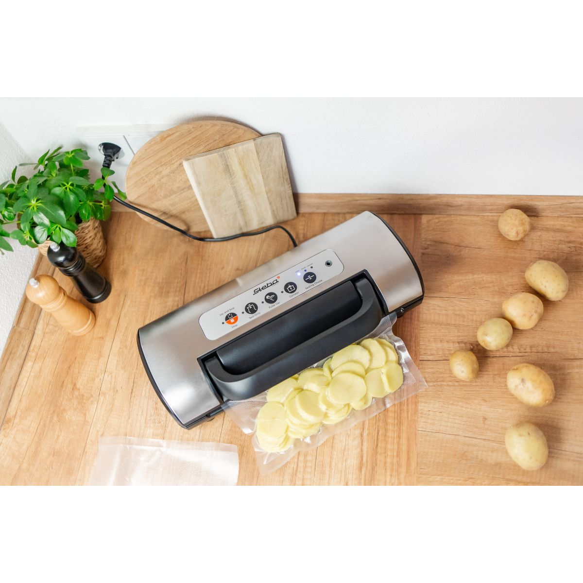 Vakuumiergerät mit Kartoffeln und Schneidebrettern.