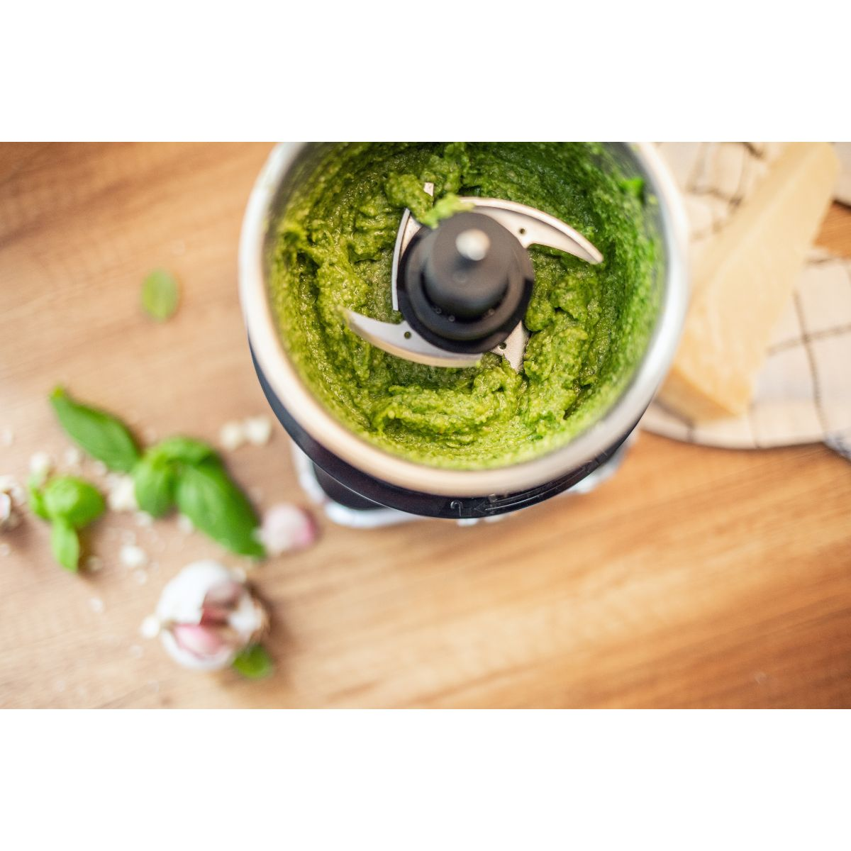 Pesto im Mixer. Basilikum, Knoblauch und Käse. Holzoberfläche.