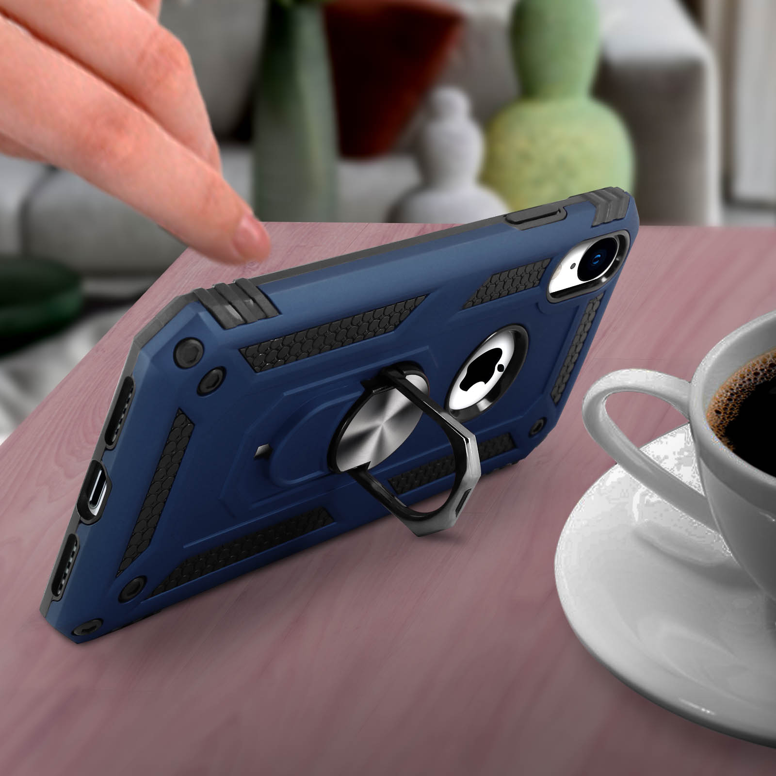 Blauwe telefoonhoes met zilveren ringstandaard op een tafel met koffie.