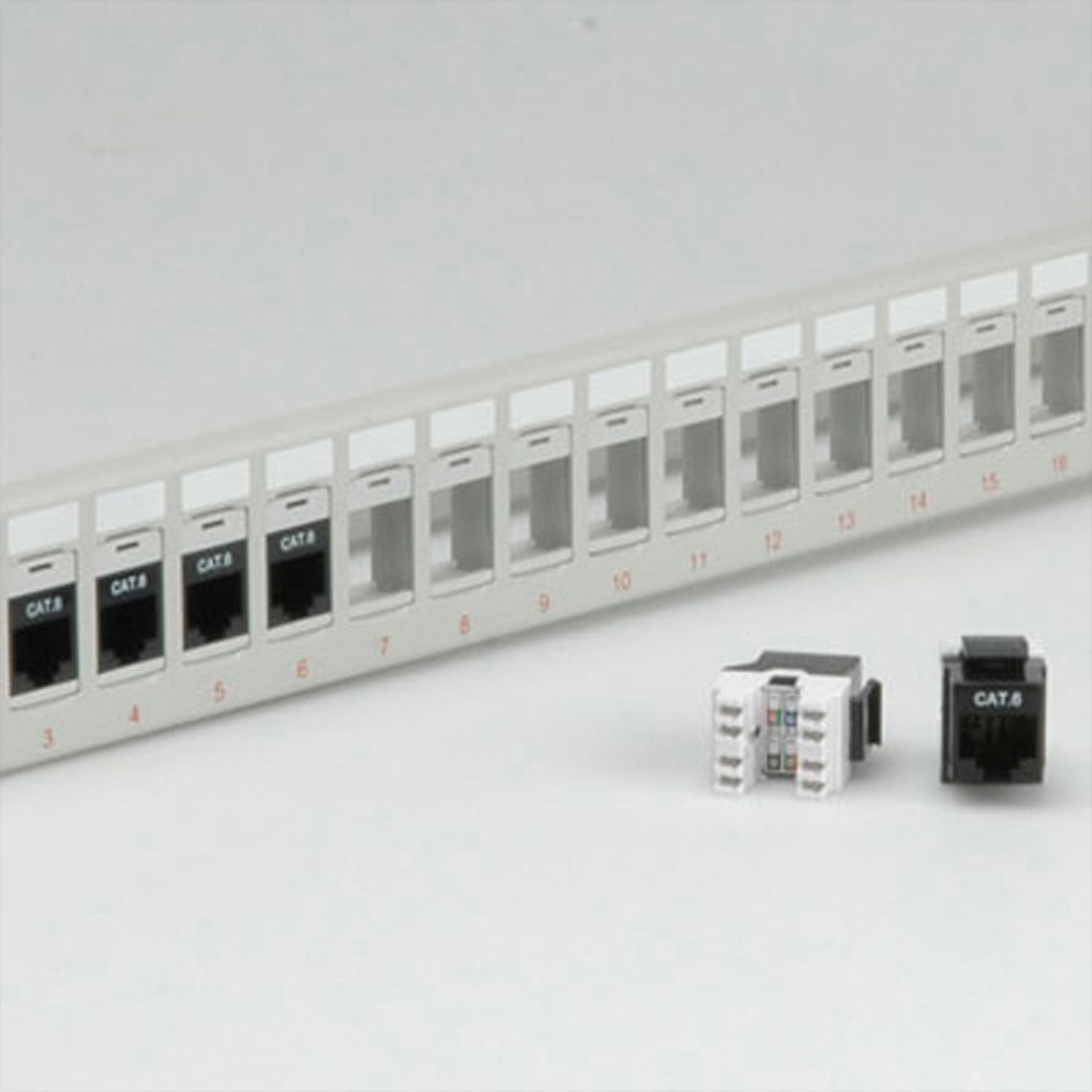 Ein weißes Patchpanel mit nummerierten Anschlüssen und zwei CAT6-Anschlüssen auf weißer Oberfläche.