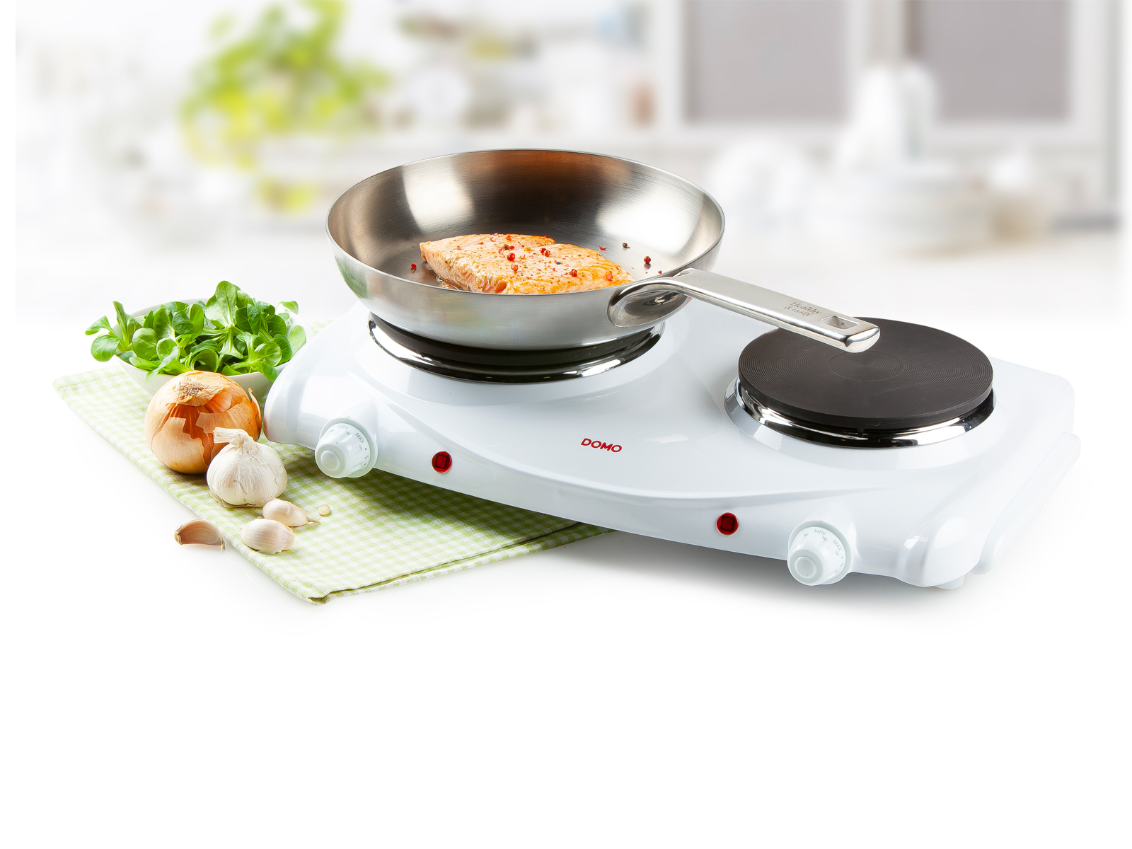 Kuchenka elektryczna z patelnią z jedzeniem, otoczona składnikami na białym tle.