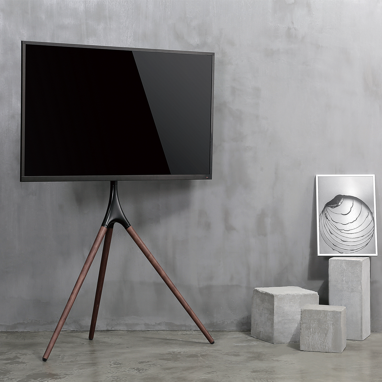 Een moderne tv-standaard met een grote tv. De standaard heeft een houten basis en drie poten. Betonnen blokken aan de zijkant.