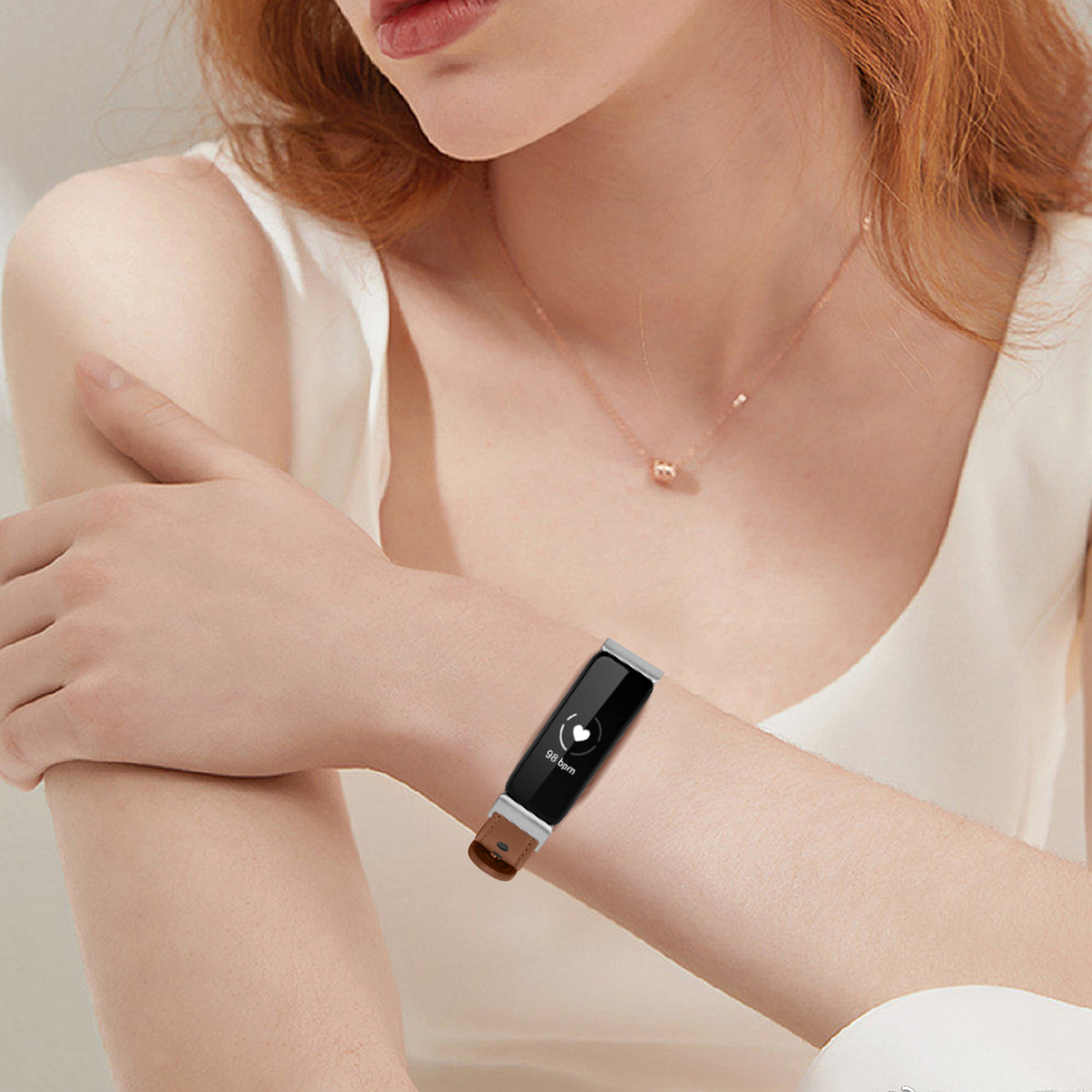 Eine Frau trägt einen schwarzen Fitness-Tracker mit Lederarmband. Der Tracker zeigt Herzfrequenzinformationen.