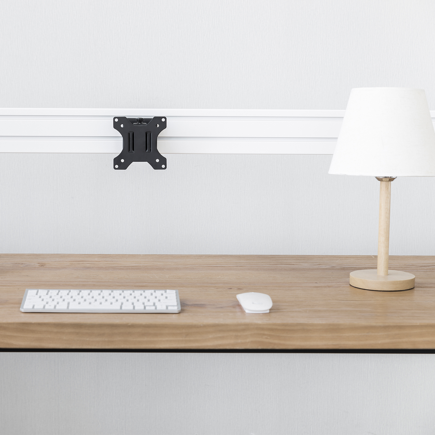 Un escritorio con teclado, ratón, lámpara y un soporte para monitor.