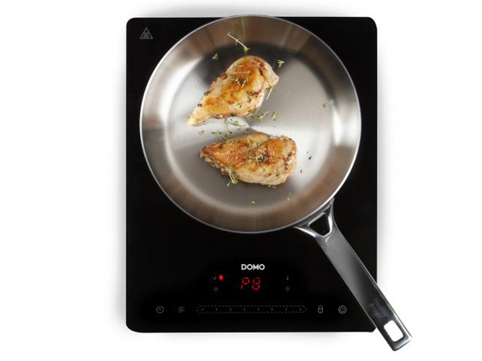 Piersi z kurczaka na patelni na czarnej płycie indukcyjnej. Zioła na jedzeniu.