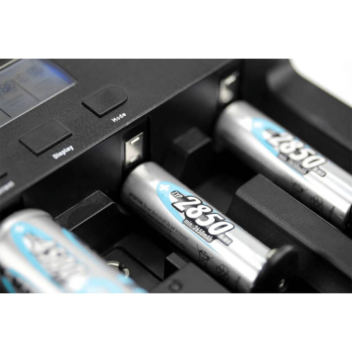 Ein Batterieladegerät mit drei zylindrischen Batterien. Display und Modustasten sichtbar.
