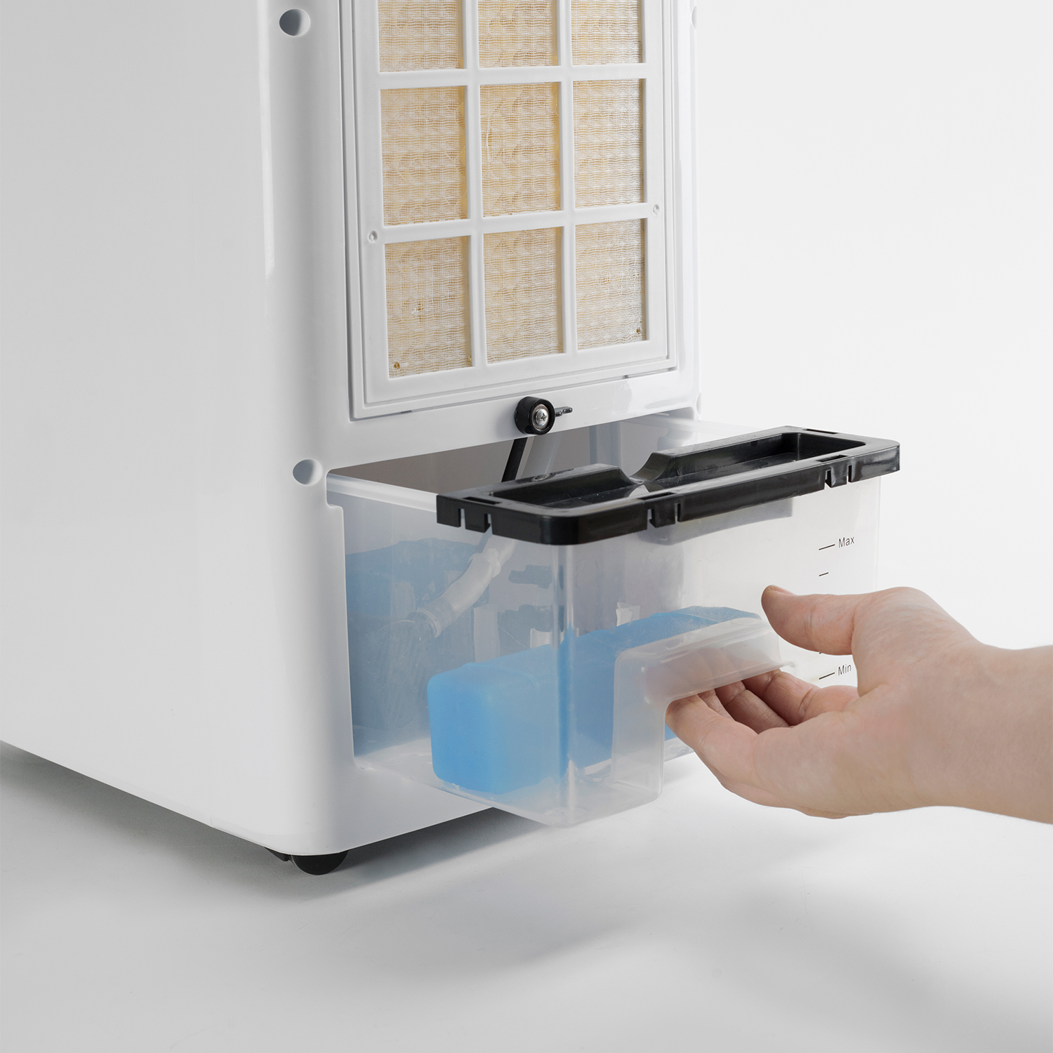 Ręka wyciągająca plastikowy pojemnik z białego urządzenia, widoczne kostki lodu.