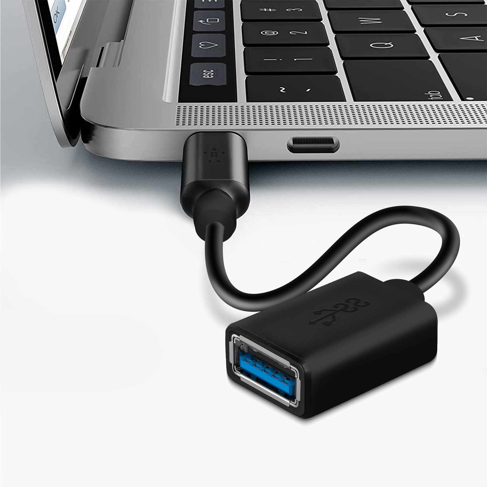 Adaptador USB-C negro conectado a una computadora portátil, que muestra un adaptador negro con un puerto azul.