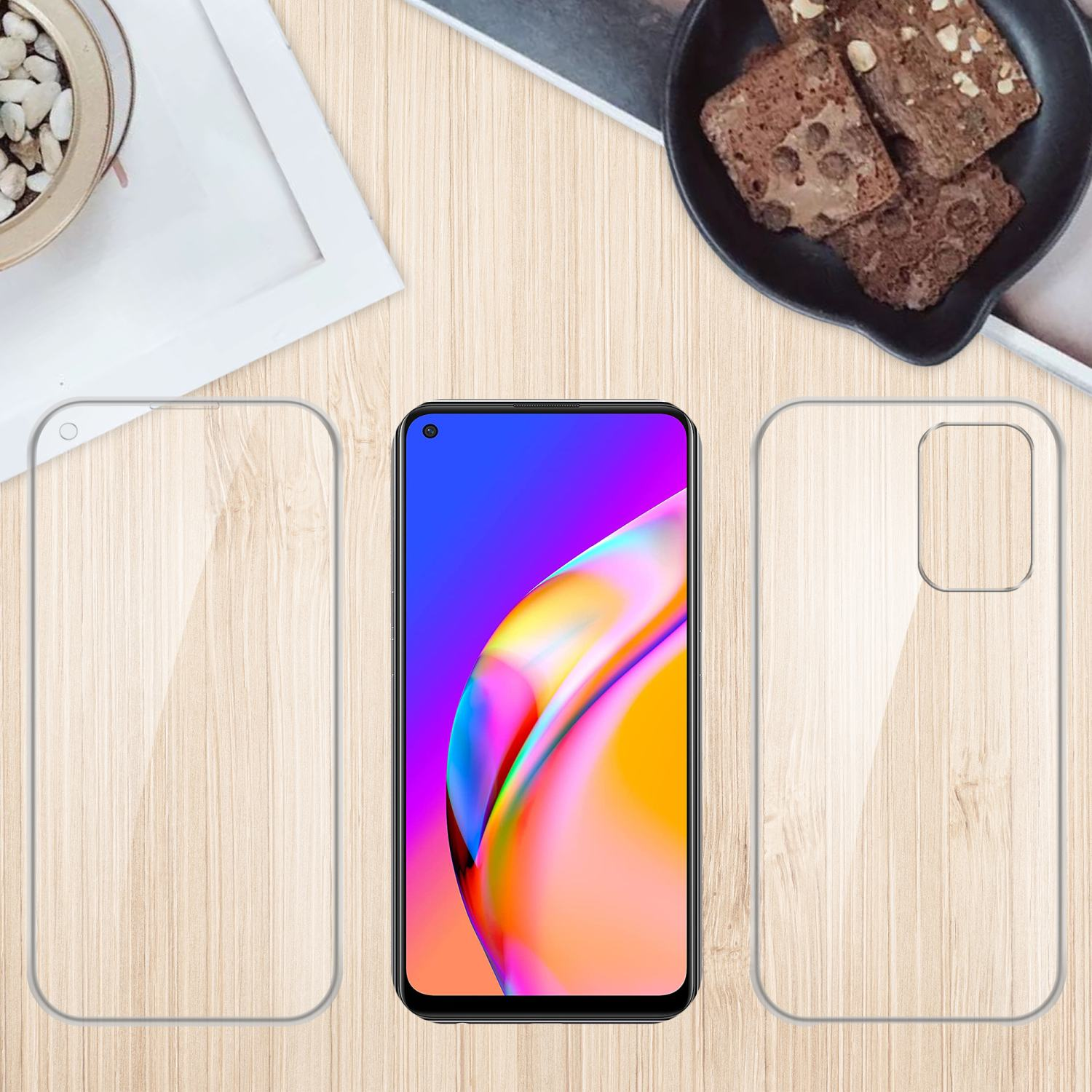 Telefono con schermo colorato, due custodie trasparenti, una piccola pianta e brownies su un tavolo di legno.