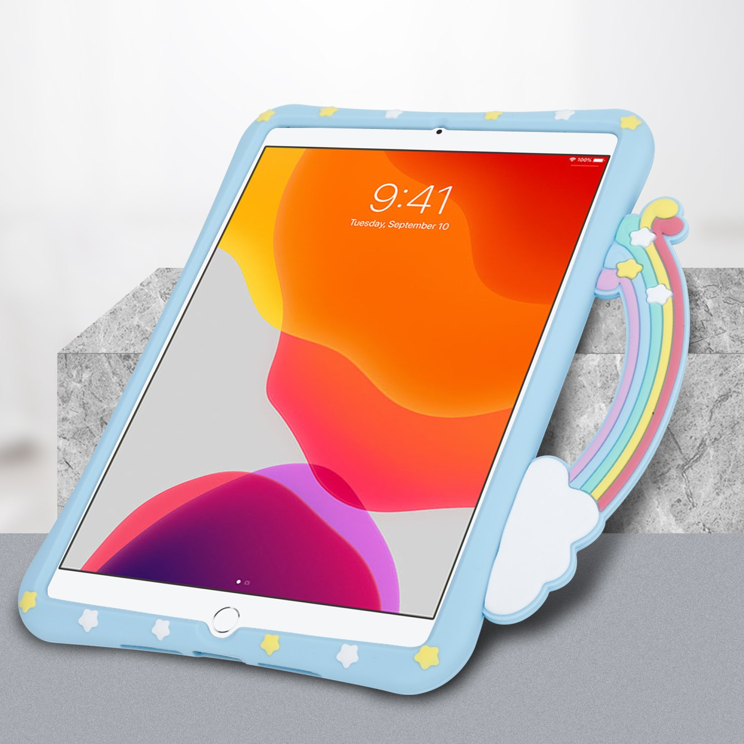 Ein iPad in einer blauen Hülle mit einem Regenbogen-Detail. Es liegt auf einer grauen Oberfläche.
