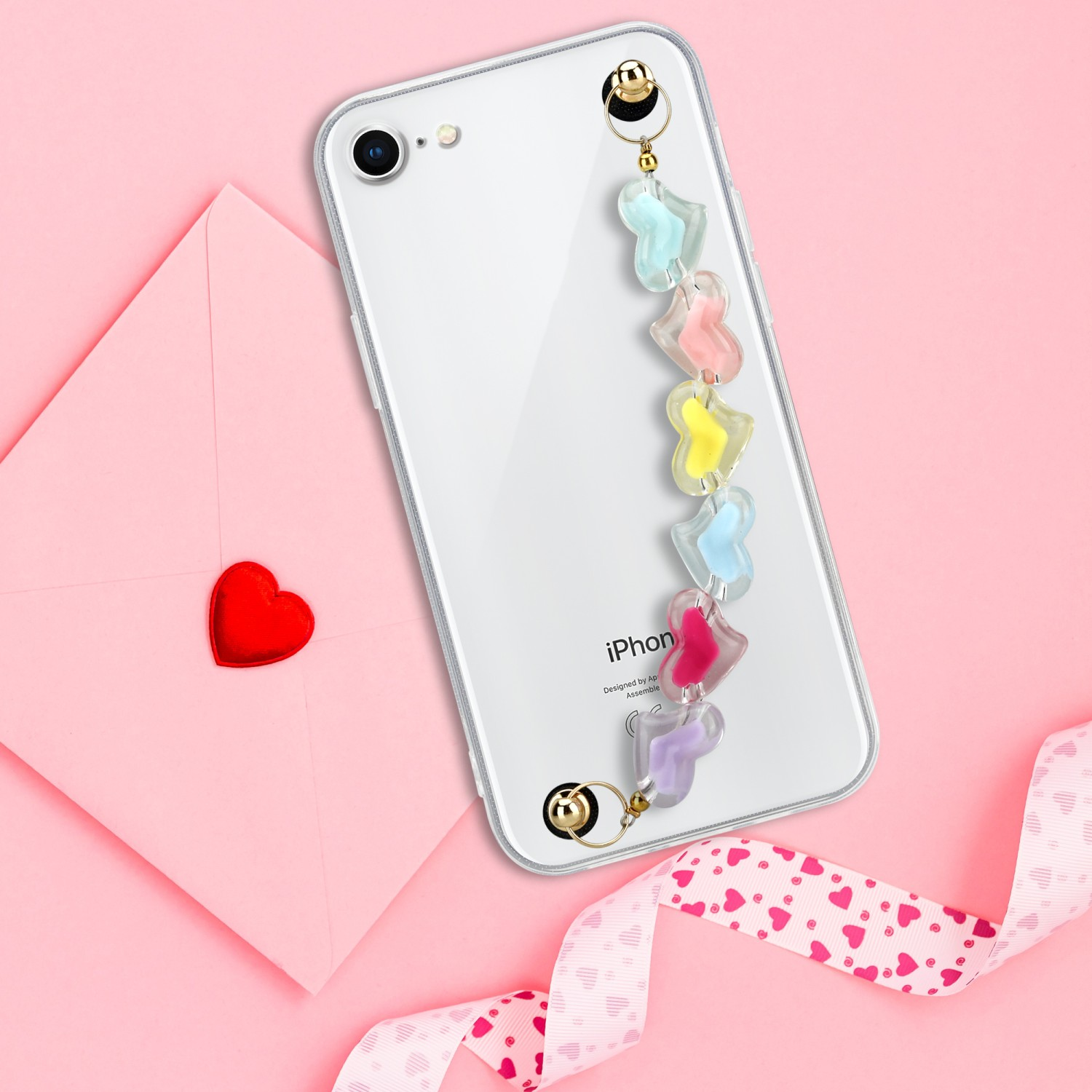 Ein Telefon mit Herzen. Ein rosa Umschlag mit Herz und Schleife ist im Hintergrund.