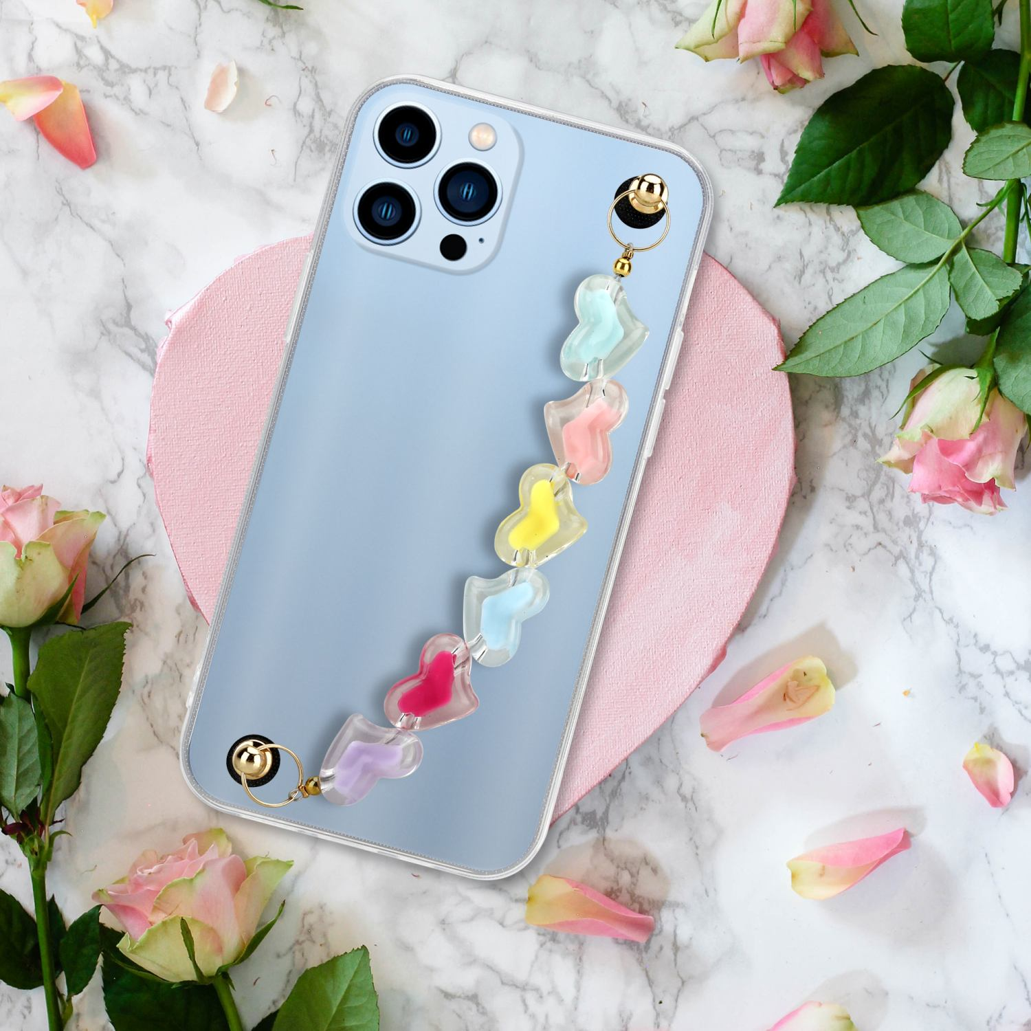Telefon mit einem Band aus bunten Herzen. Rosa herzförmige Oberfläche mit Blumen. Rosen und Blütenblätter an den Seiten.