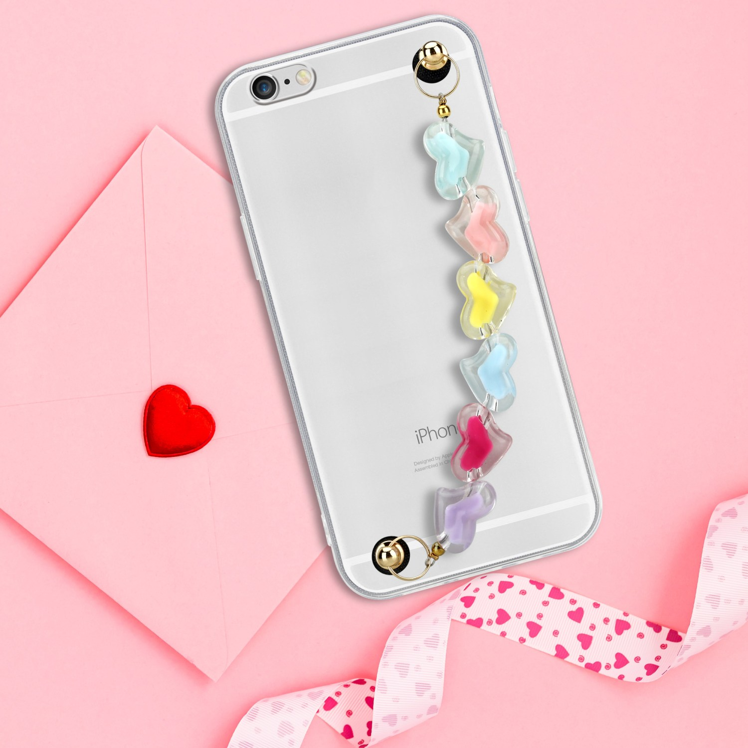 Ein transparentes iPhone mit herzförmigem Anhänger und rosa Hintergrund mit Herzmuster.