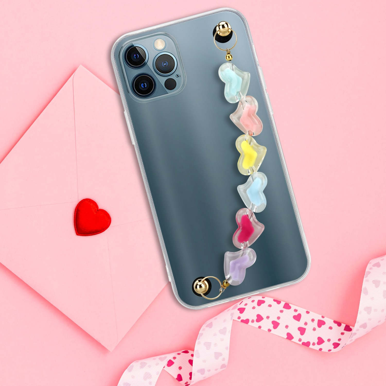 Telefon und Telefonband mit herzförmigen Anhängern auf rosa Oberfläche. Rosa Band ist auch sichtbar.