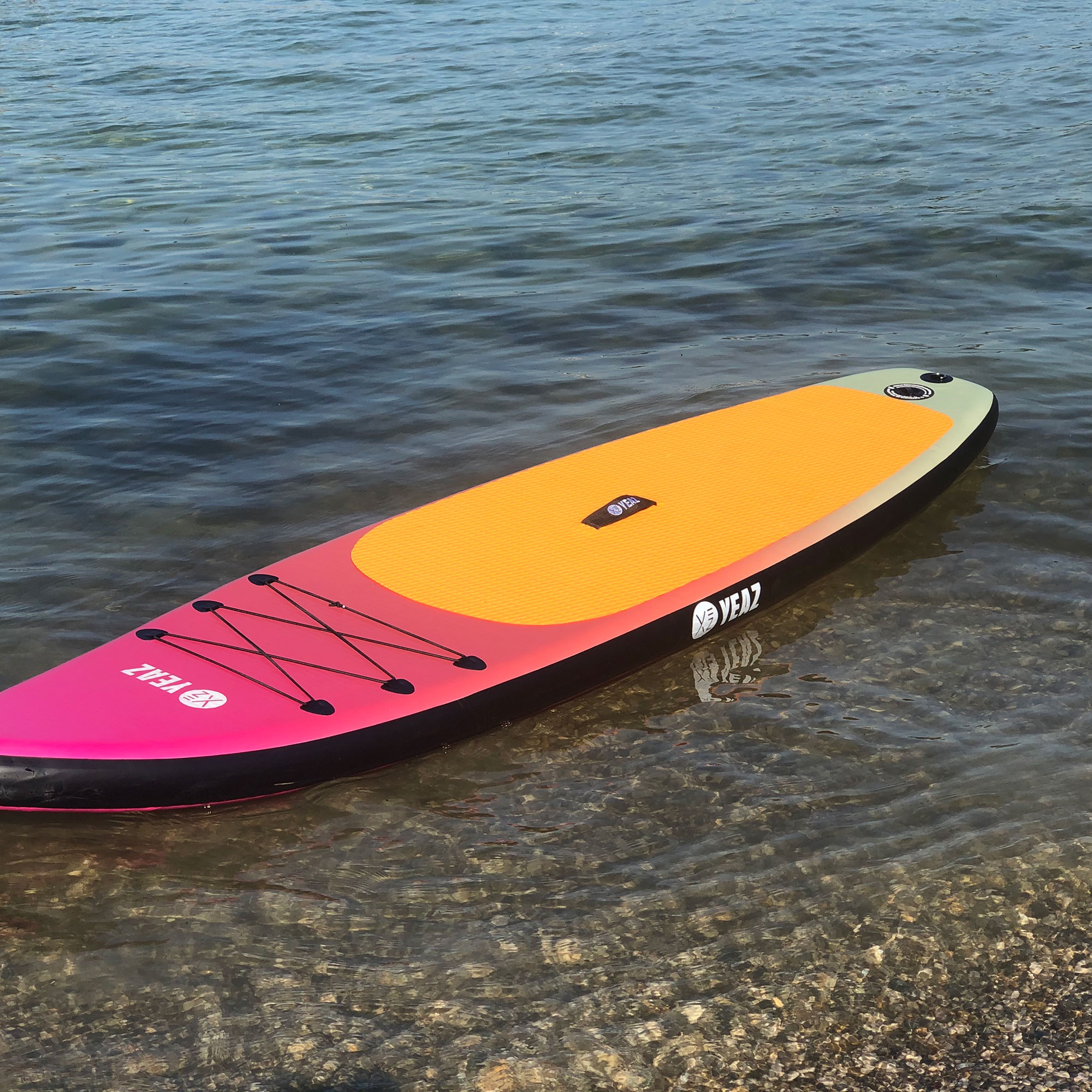 Stand-Up Paddleboard im Wasser mit pinkem und gelbem Design.