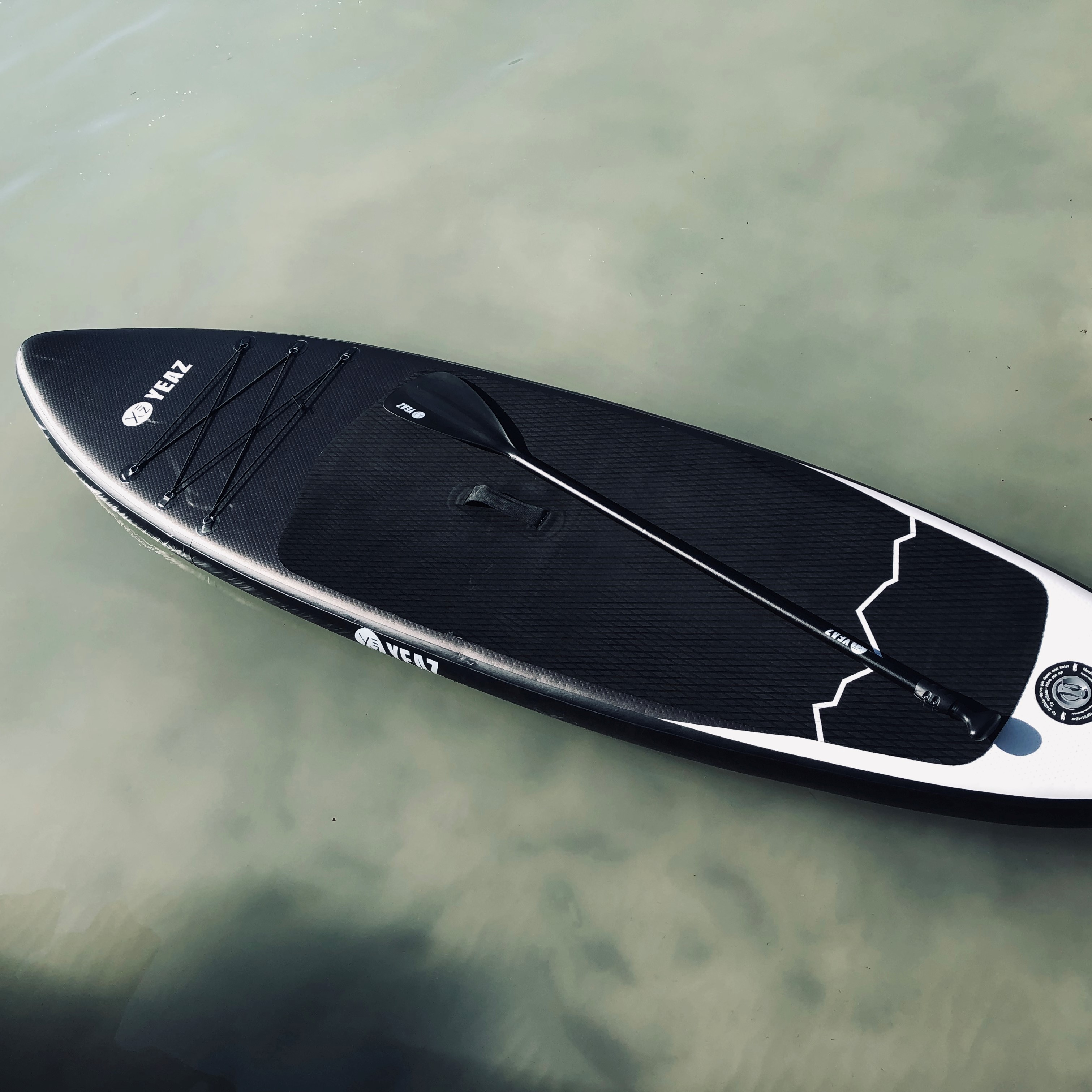 Stand-Up-Paddleboard im Wasser mit Paddel. Schwarz-weißes Design.