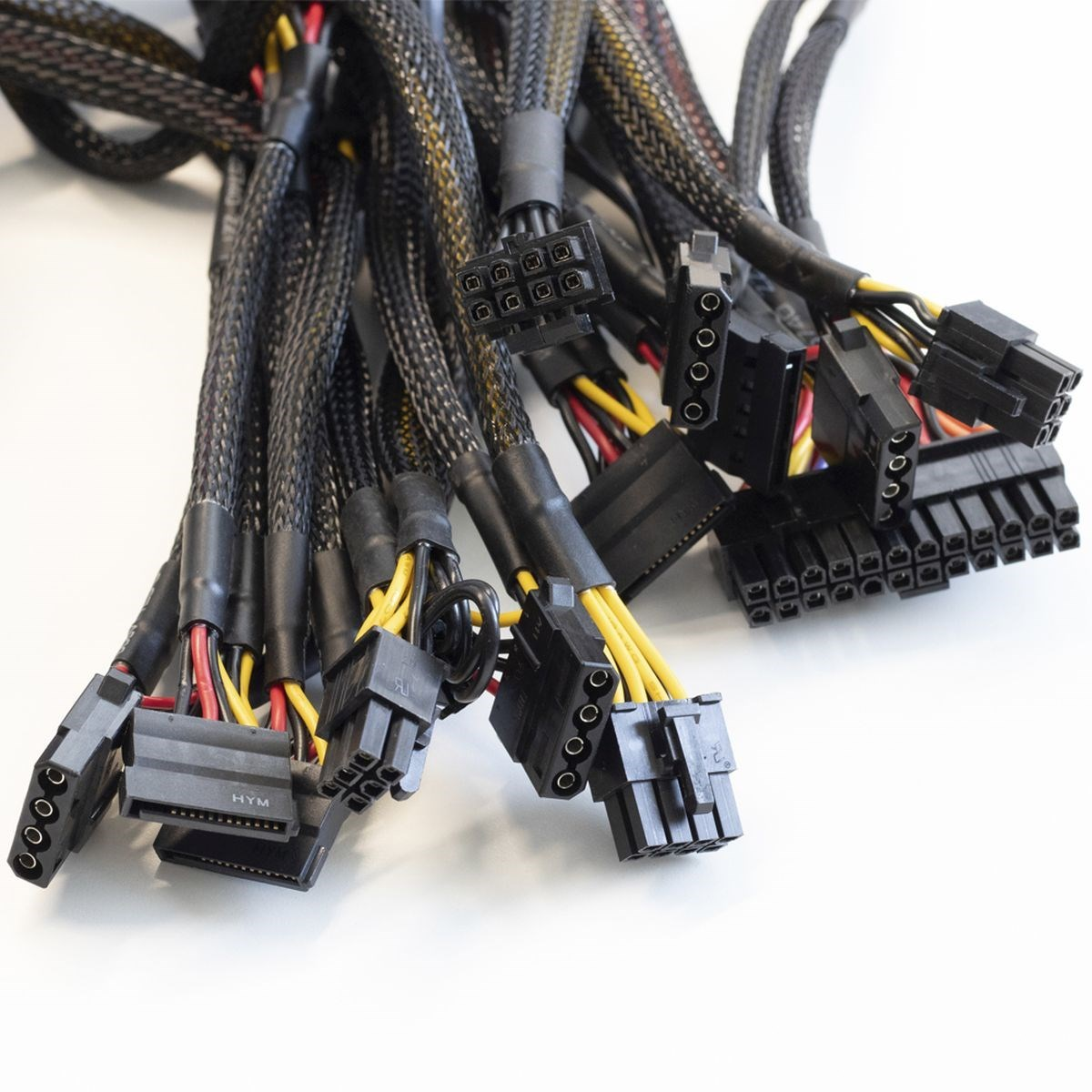 Cables de alimentación negros, muchos conectores. Cables amarillos y negros sobre superficie blanca.