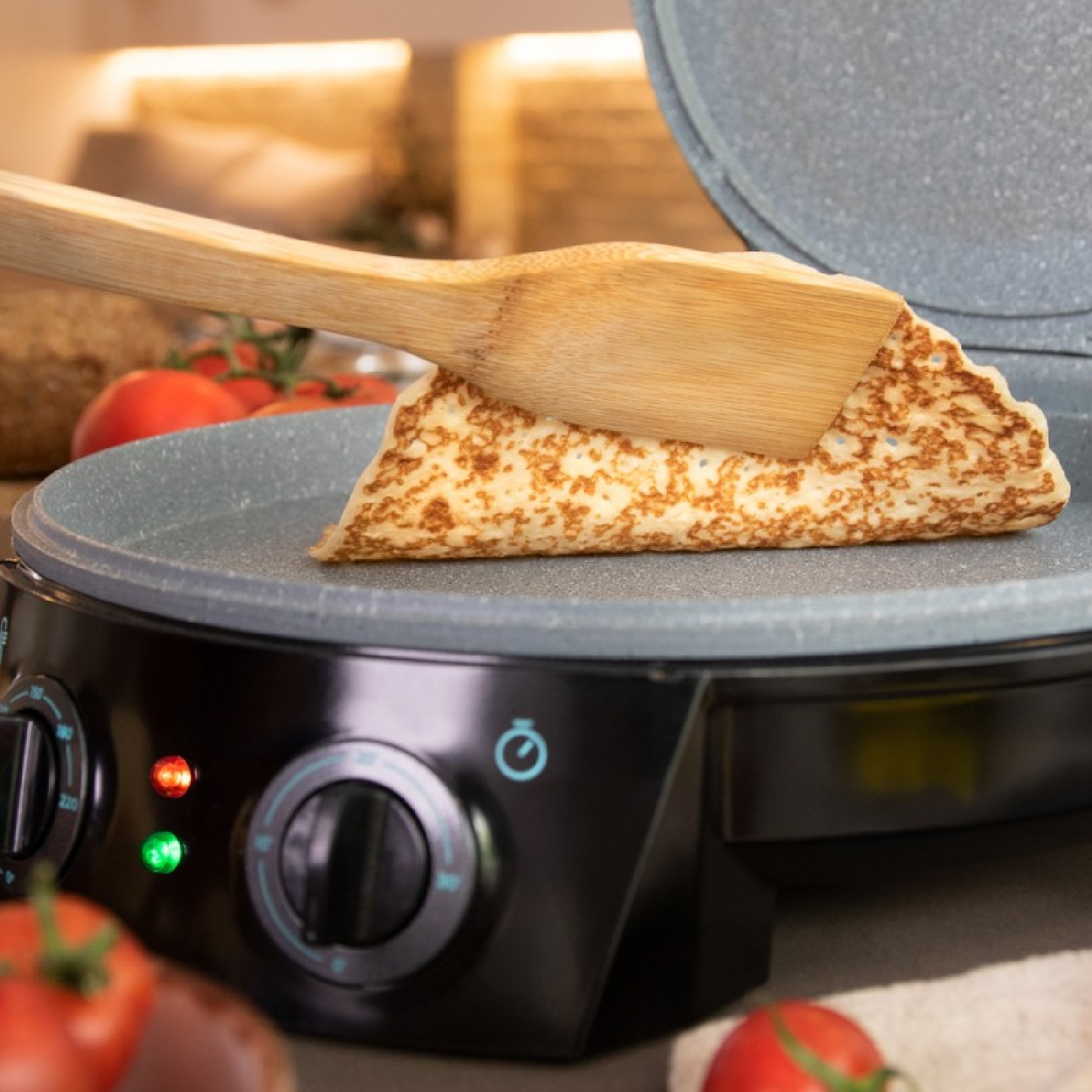 Frittella su una piastra rovesciata con una spatola di legno. Pomodori in primo piano.
