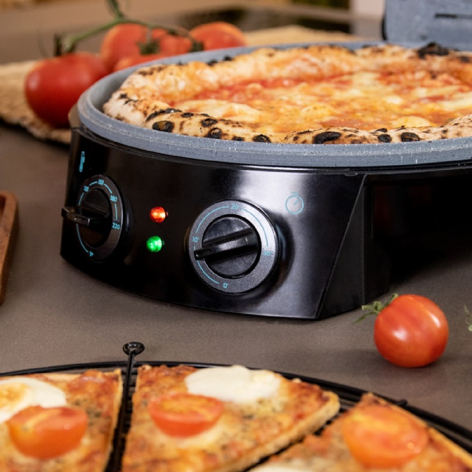 Pizza in un forno nero. Pomodori tritati e fette di pizza sono in primo piano.
