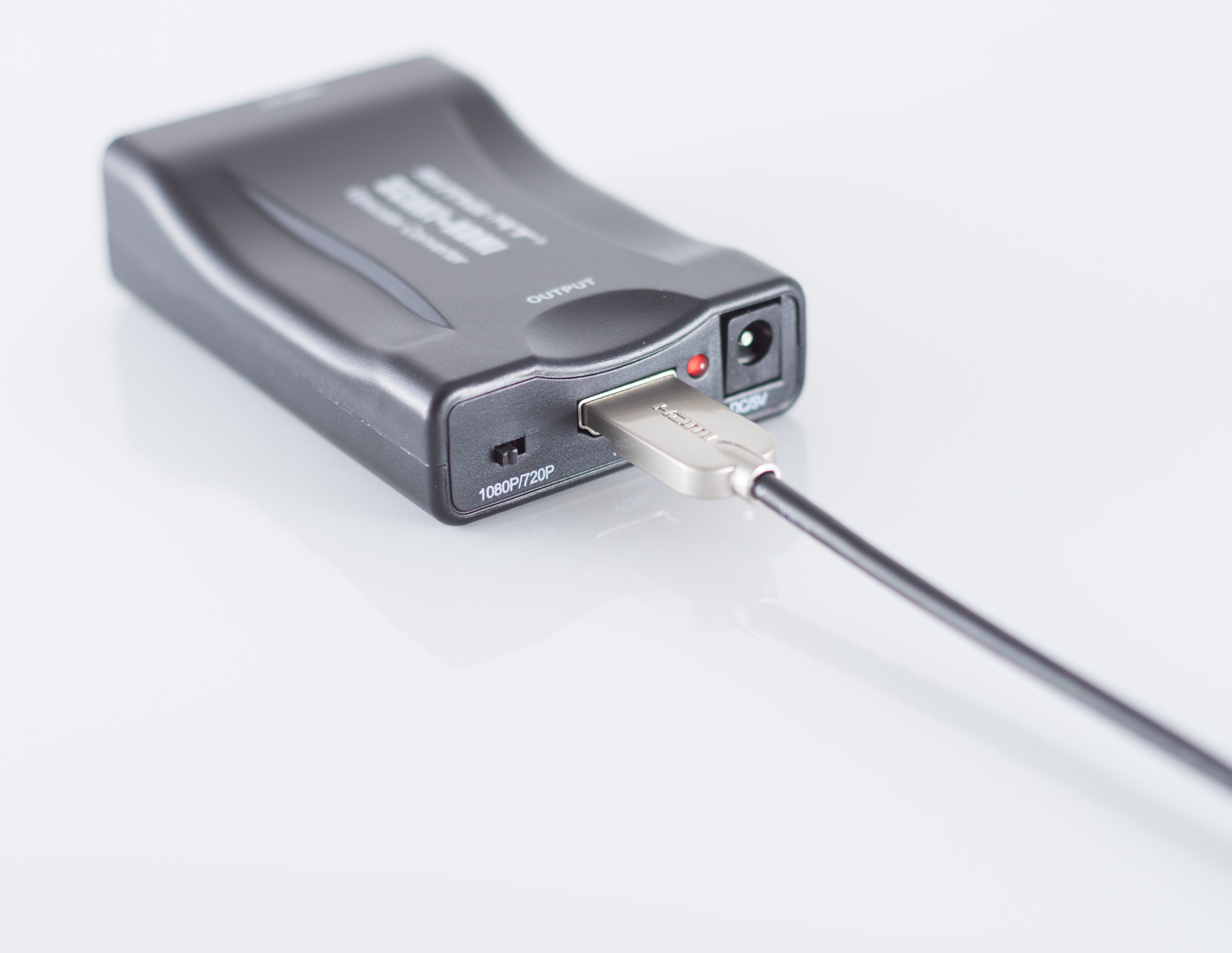 Schwarzer Konverter mit eingestecktem USB-Kabel. Das Gerät liegt auf weißem Untergrund.