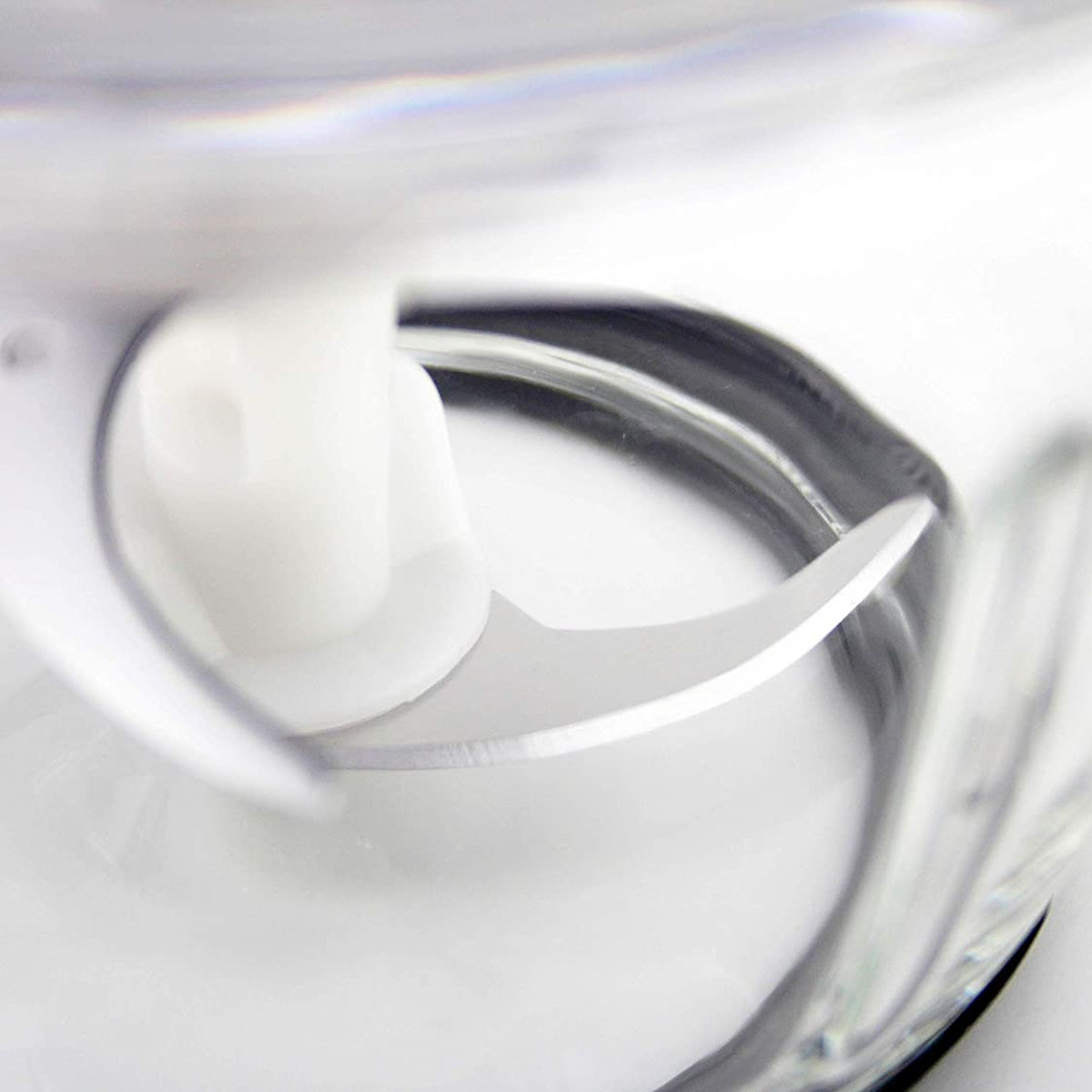 Primer plano de una cuchilla de licuadora. La cuchilla es plateada, en un recipiente blanco.