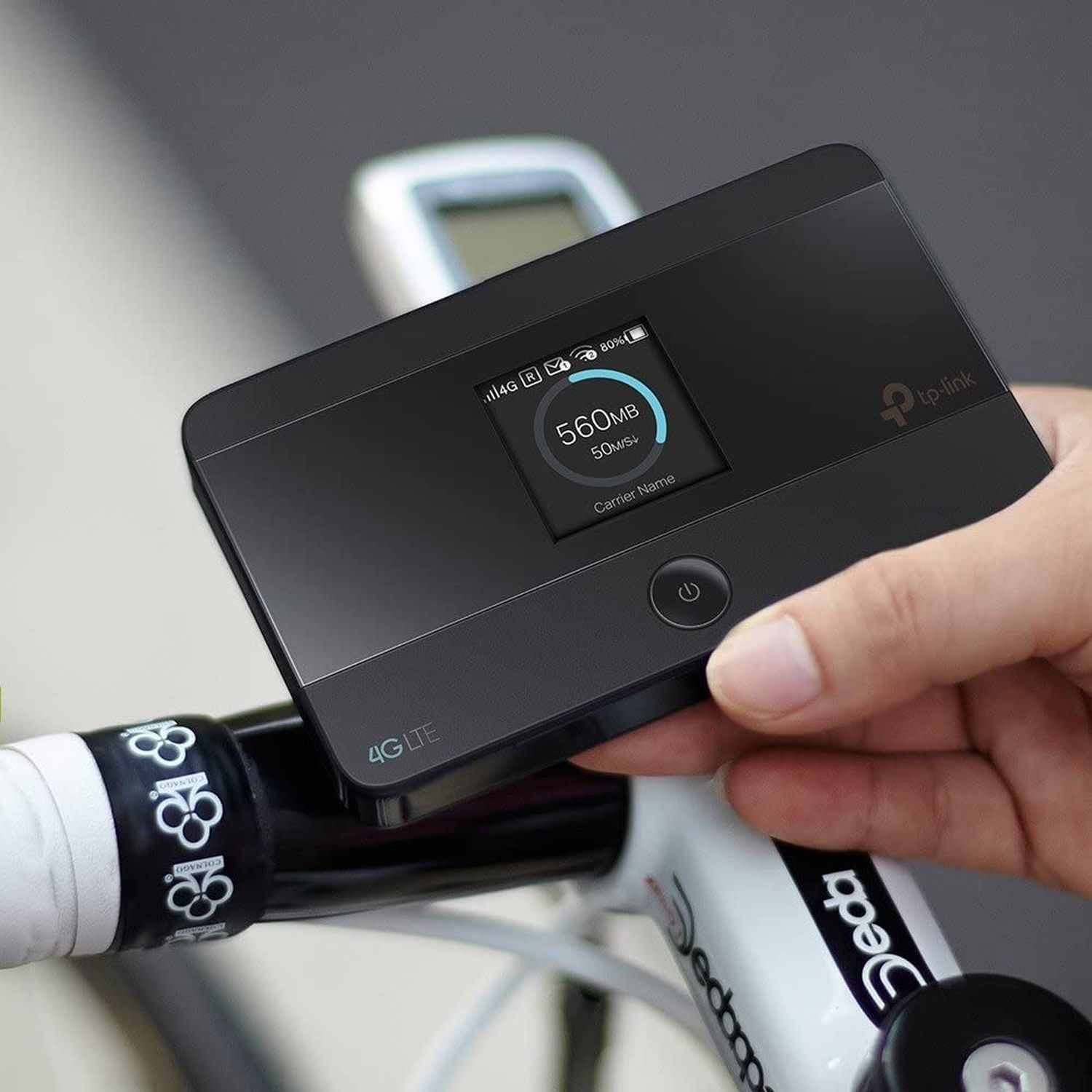 Schwarzer 4G LTE tragbarer Router auf einem Fahrrad, der Daten auf dem Bildschirm anzeigt.