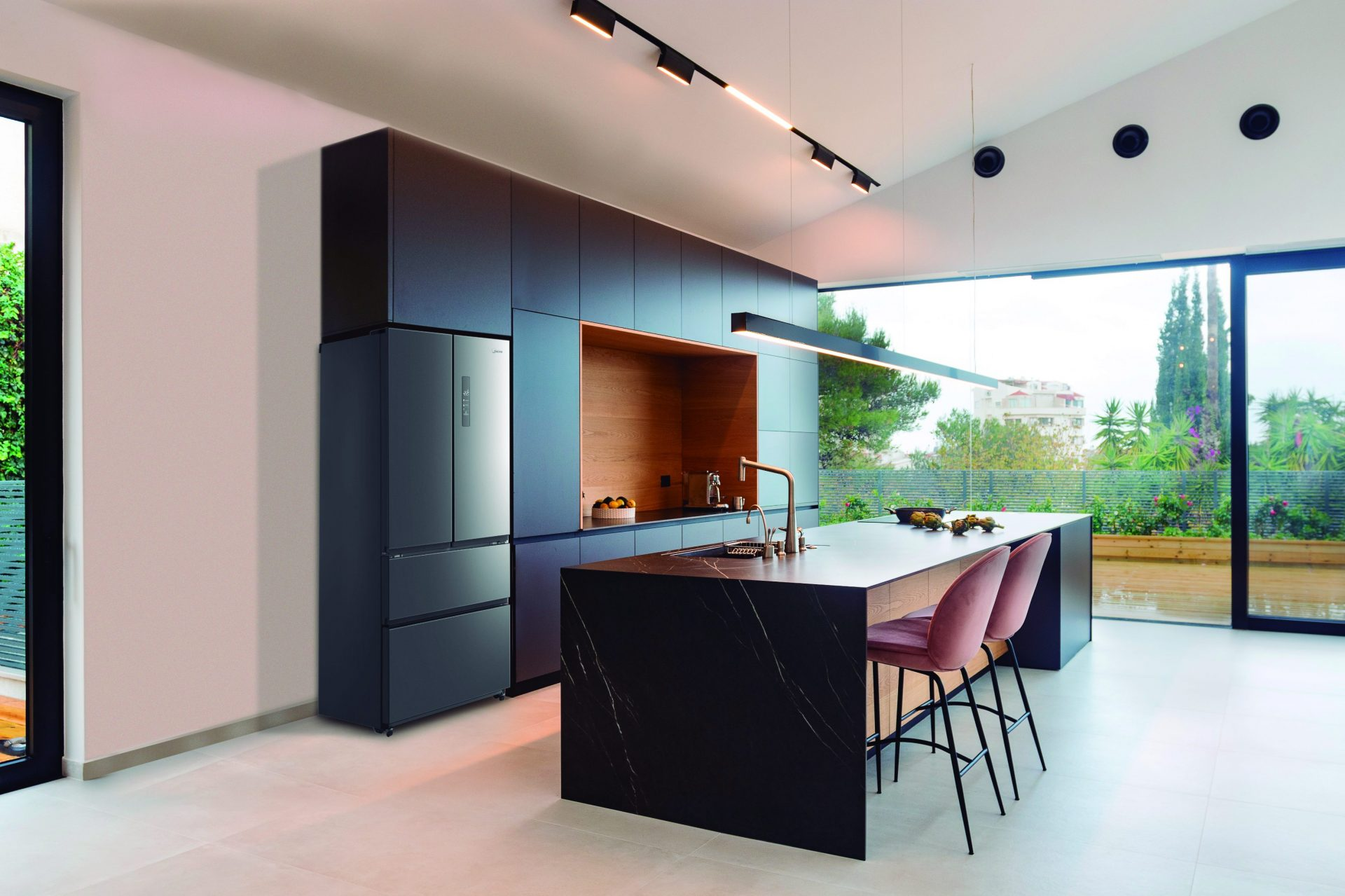 Cocina moderna con nevera, isla con taburetes y una ventana grande.
