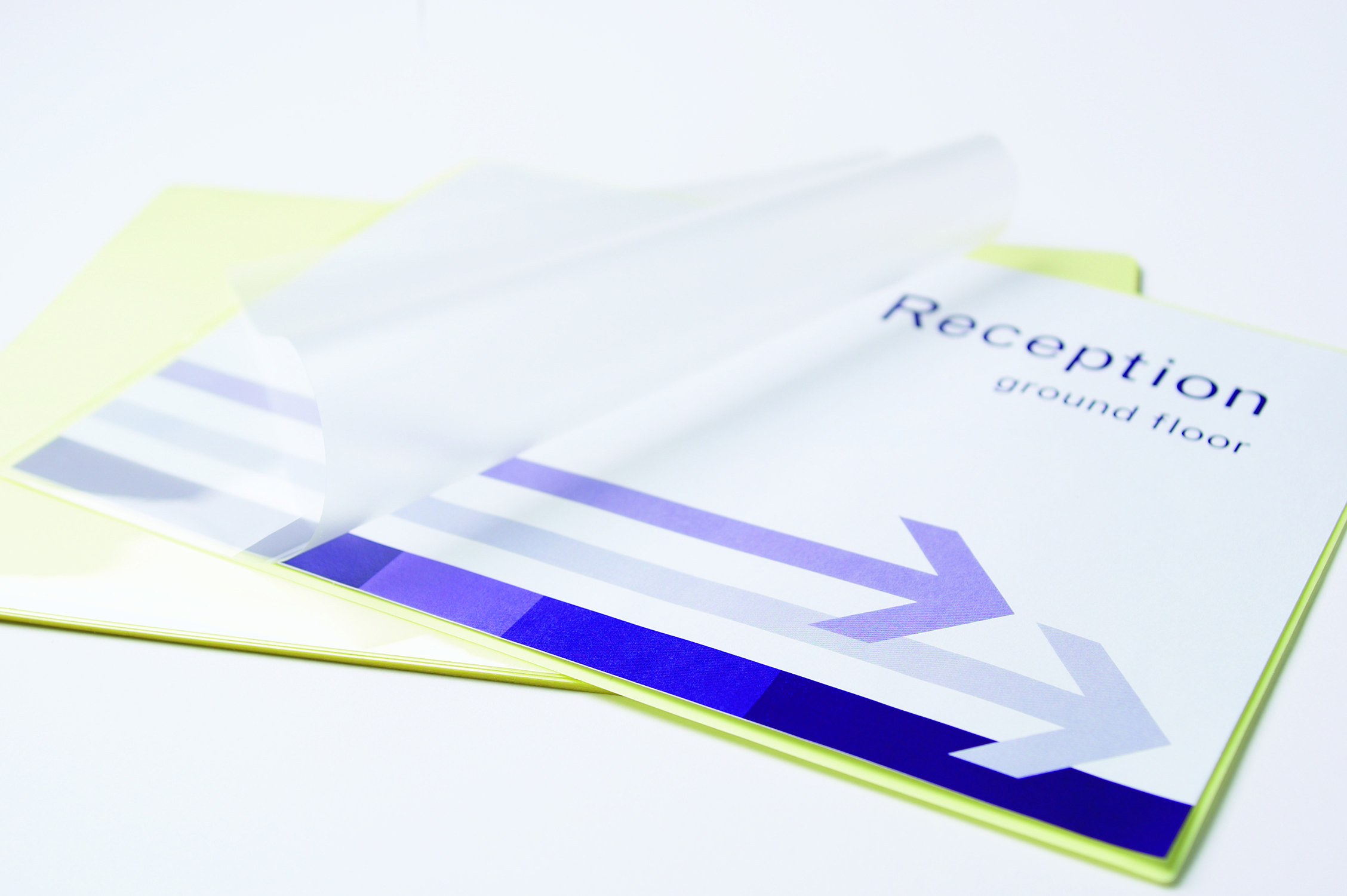 Papier mit 'Rezeption' Text und Pfeilen, teilweise von transparentem Kunststoff bedeckt. Gelbes Papier darunter.