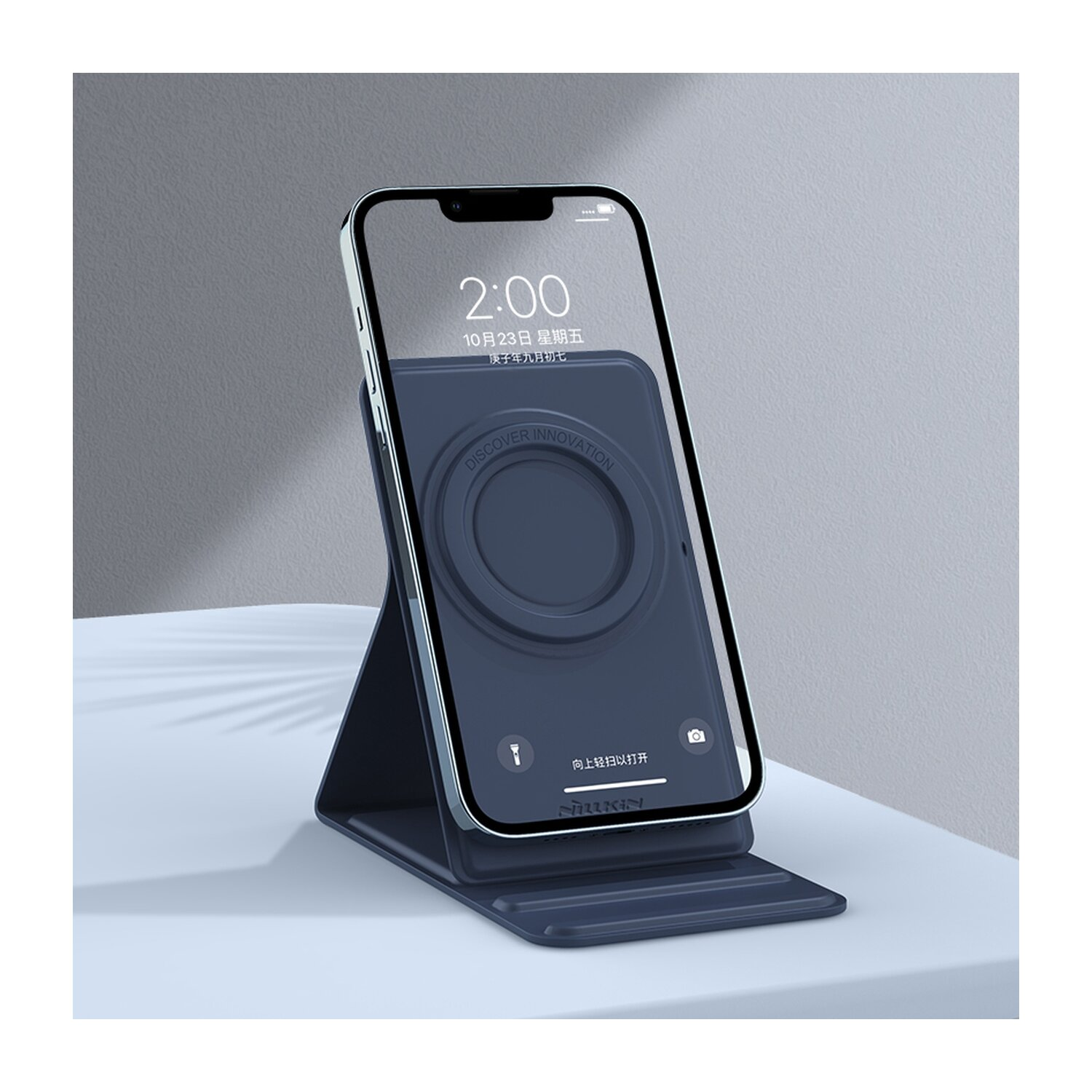 Telefon auf Ständer, Bildschirm sichtbar. Ständer marineblau, Telefon zeigt Zeit. Hintergrund ist schlicht.