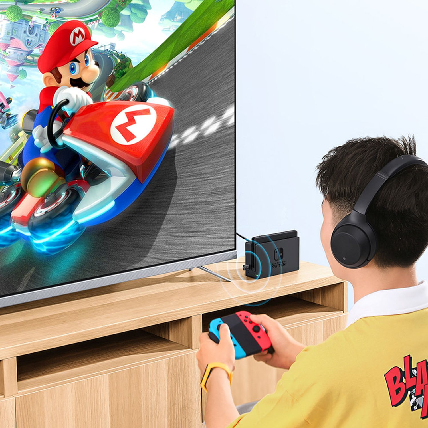 Mężczyzna gra w grę z kontrolerem. Gra Mario Kart jest w telewizji.